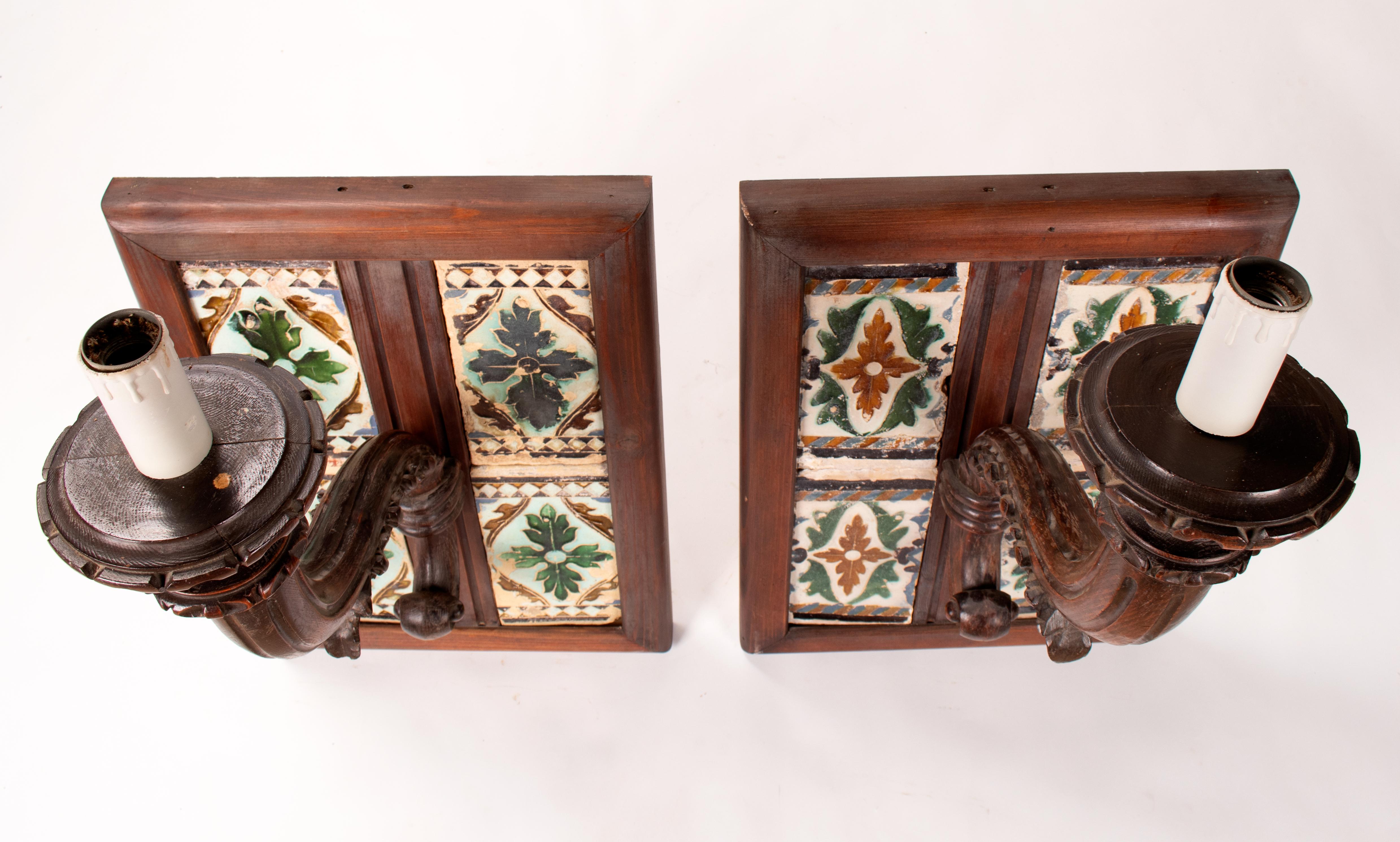 19th century pair of Spanish wooden wall lamps with 16th century cuerda seca glazed ceramic tiles. 

When different coloured glazes are applied to a ceramic surface, the glazes have a tendency to run together during the firing process. In the