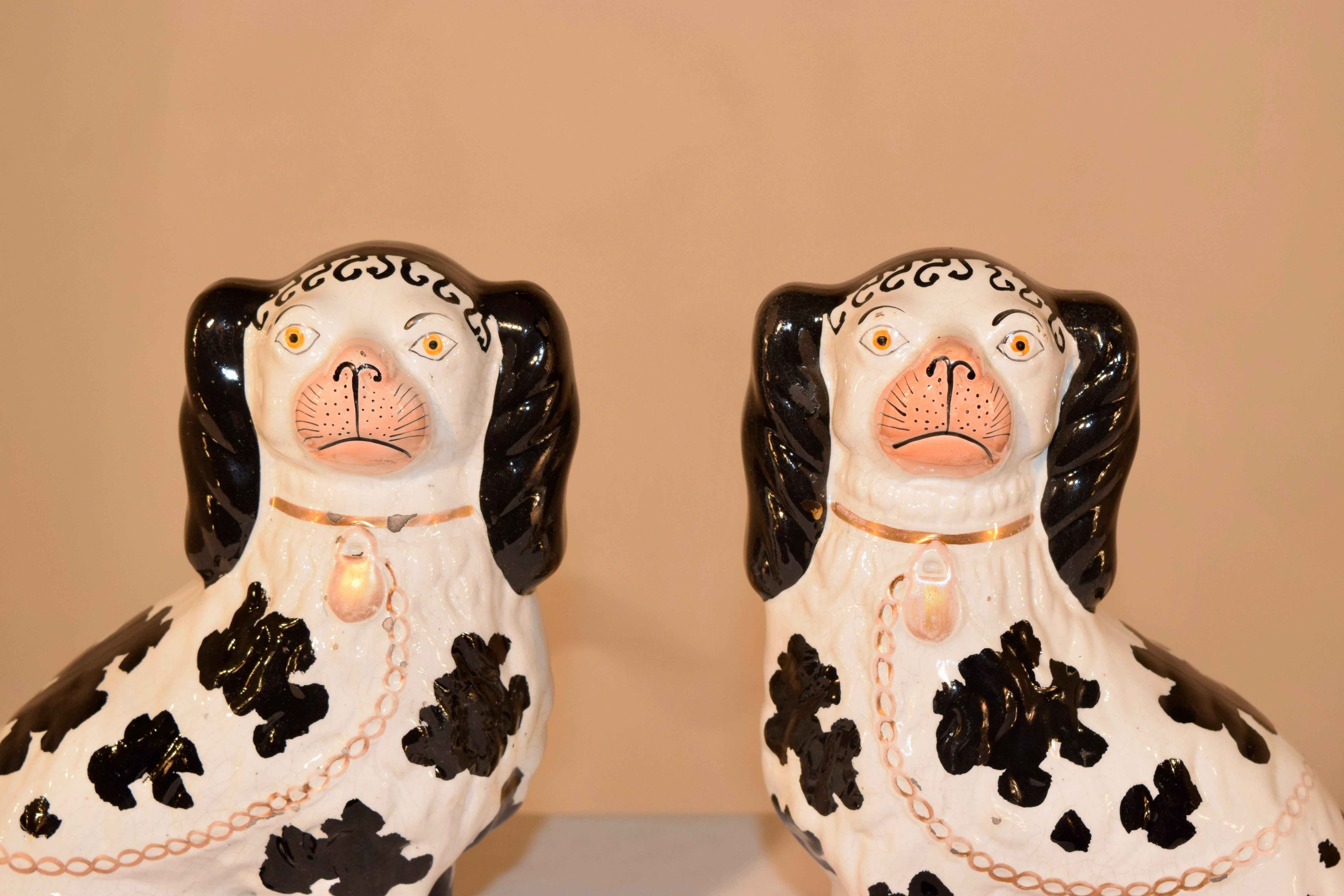 19th century pair of Staffordshire spaniels in the Disraeli style. The spaniels have separated front legs, and are painted in a black and white design. The design is named after Benjamin Disraeli, who was the Prime Minister to England twice during