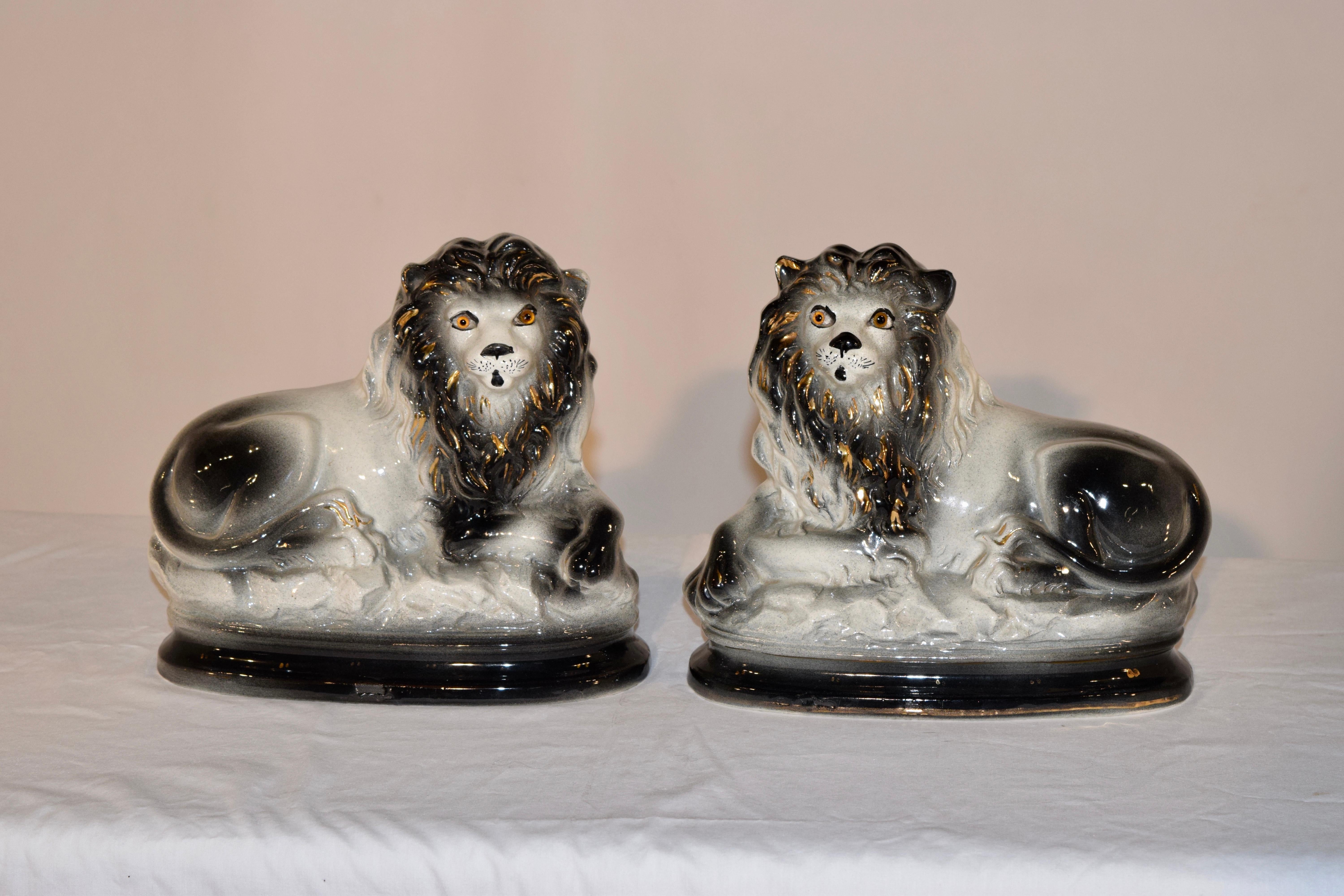 Late 19th century pair of English Staffordshire lions in an unusual black and white coloration with gilt decoration and glass eyes.
