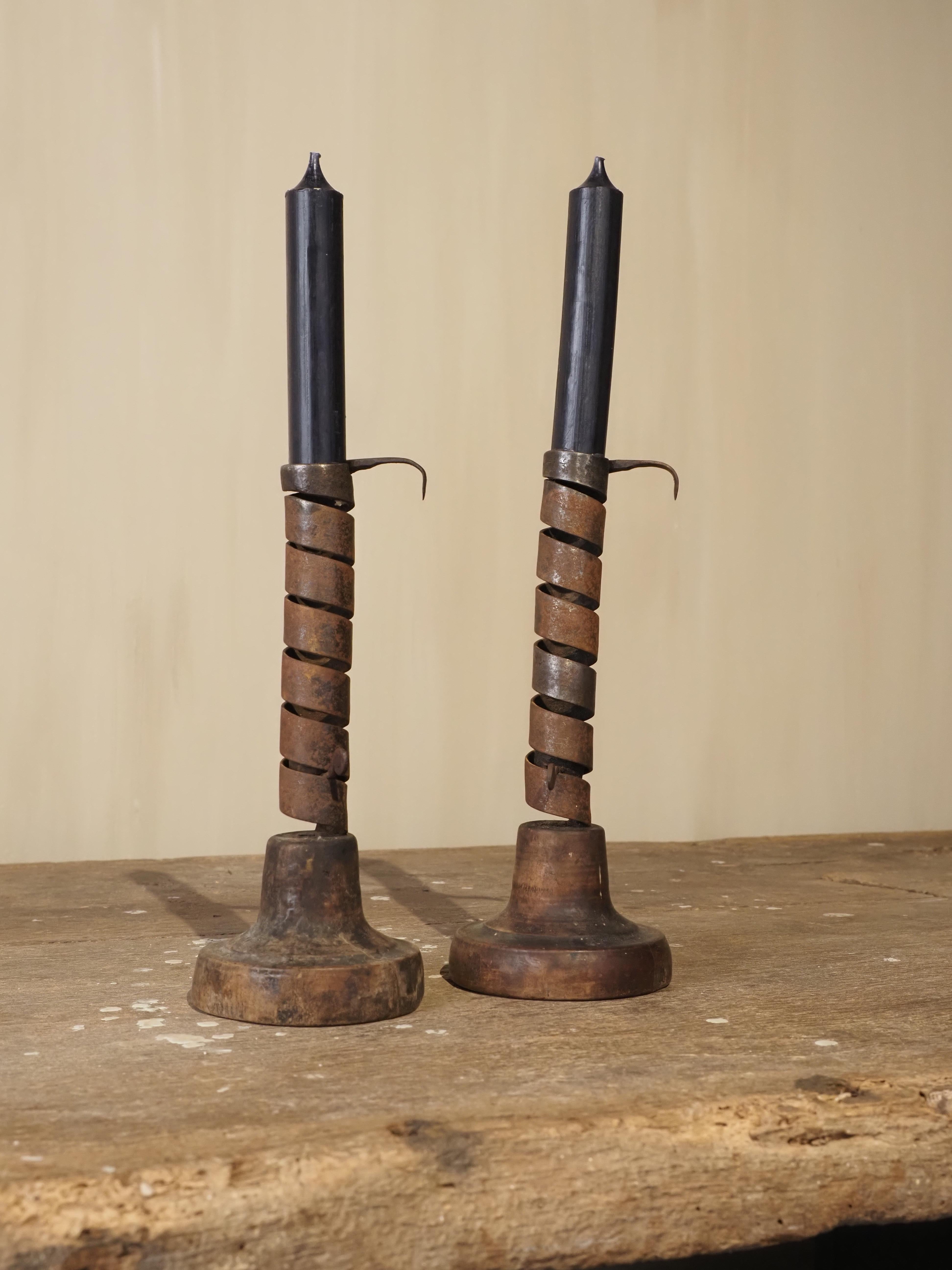 A rare and exquisite pair of rat de cave candlesticks, hand-forged in wrought iron with wooden details, originating from Normandy, France, 19th century.
Expertly crafted by hand, they feature the traditional spiral stem mechanism designed to adjust