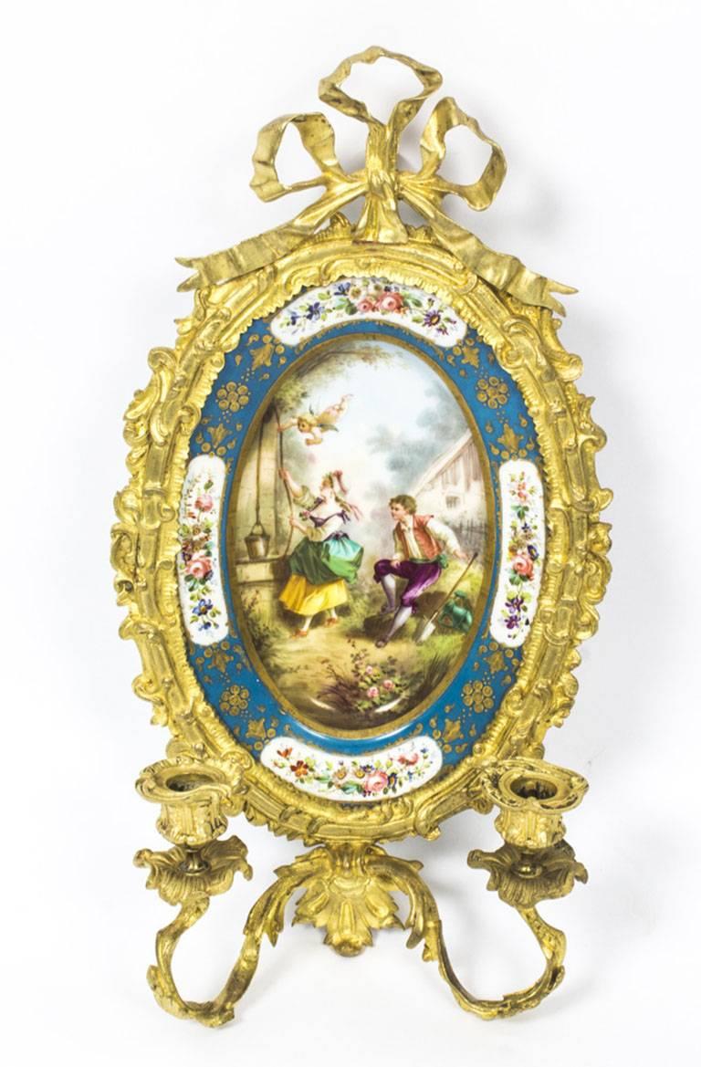 This is a stunning Antique pair of Sevres porcelain and ormolu wall lights, circa 1870 in date.
 
They feature an elegant classical frame with a ribbon crest and upturned scrolling acanthus two branch arms with foliate cast sconces.

They