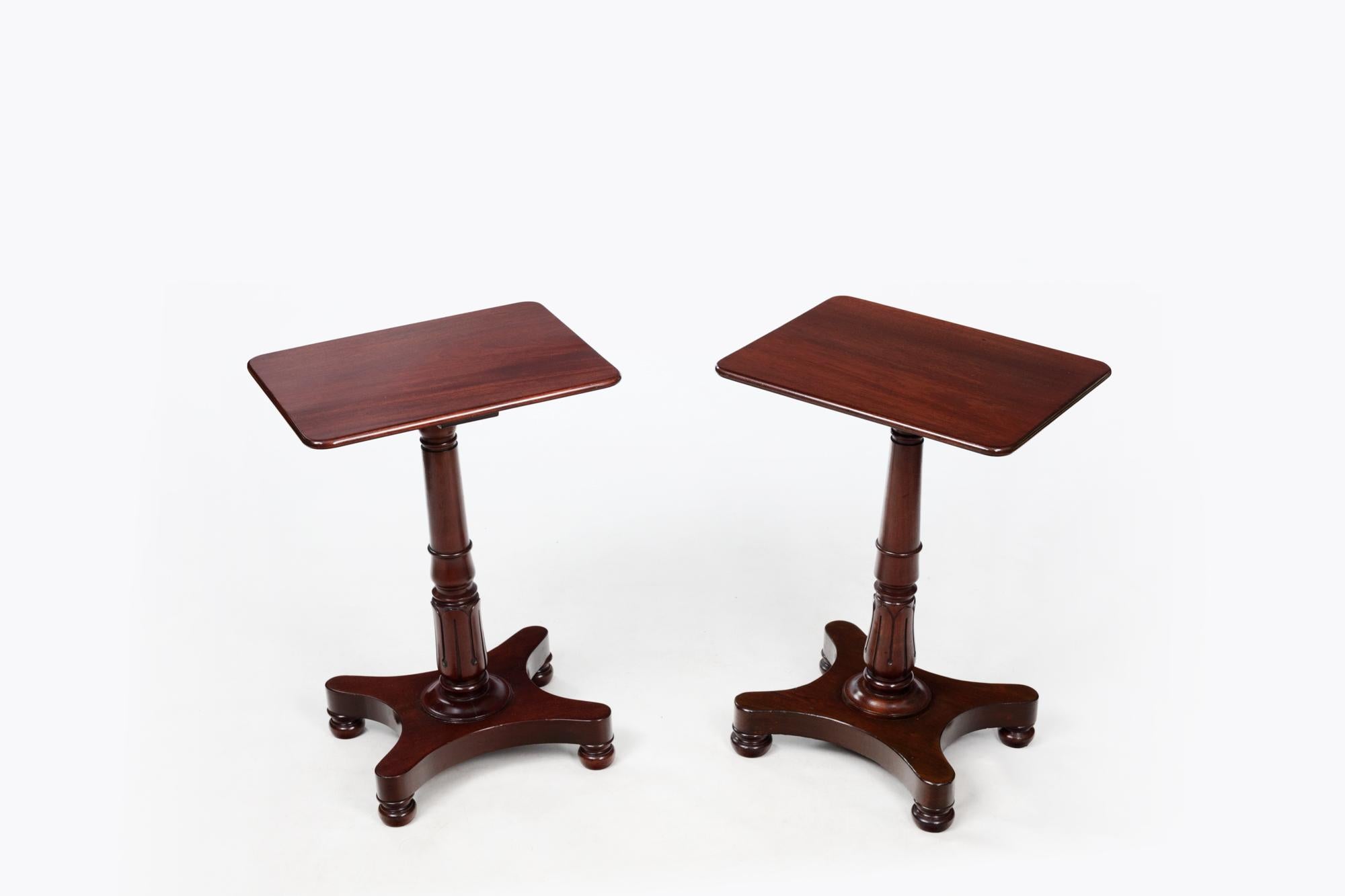 19th Century Pair of William IV Mahogany End Tables with rectangular top sitting above gun barrel column featuring carved foliate motif to base. Supported by a platform base terminating on four bun feet.