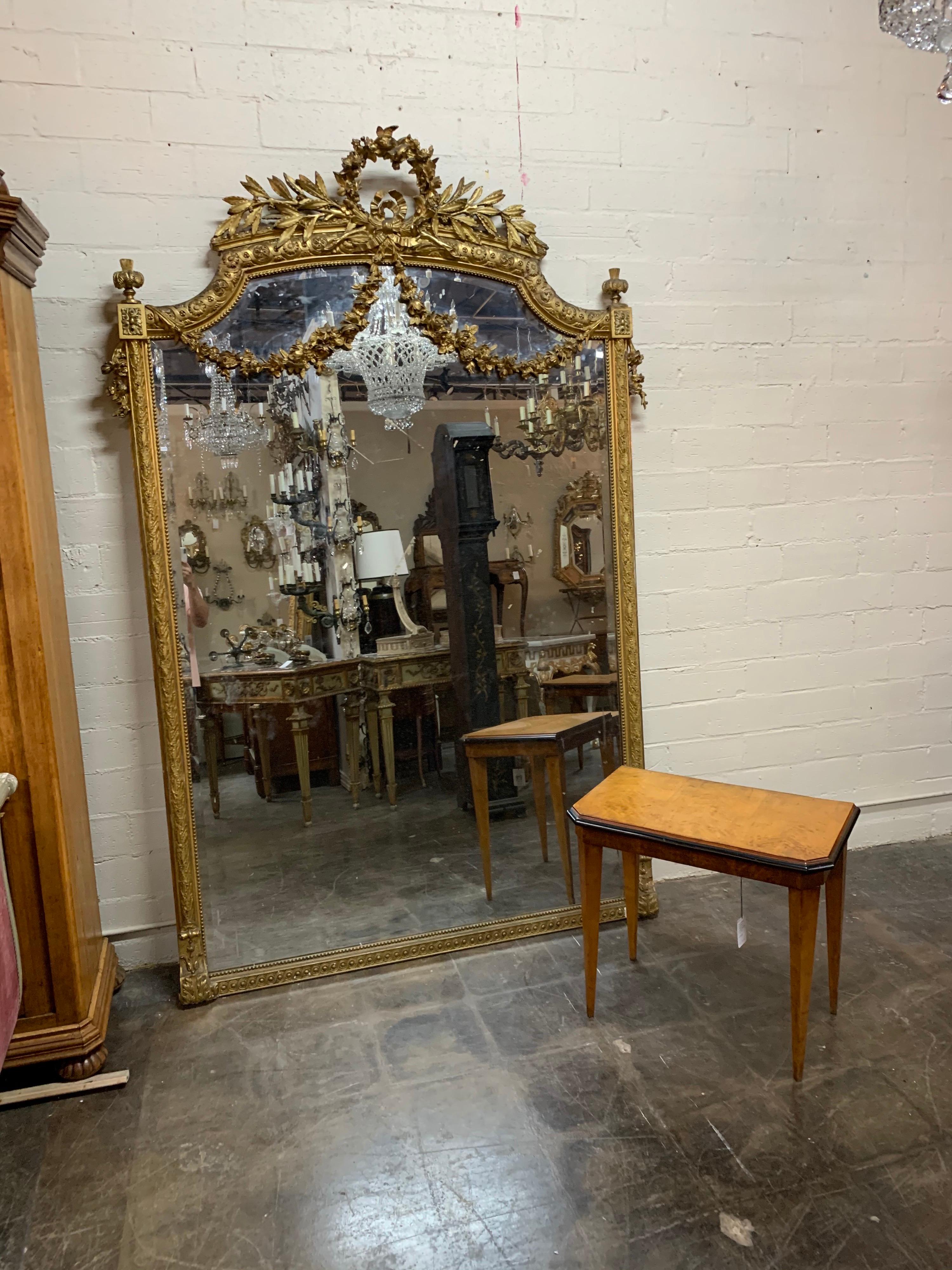 Exquisite 19th century palace size carved and giltwood Louis XVI style mirror. Featuring beautifully carved floral images and urn like shapes on the top corners. The outside border of the mirror also has amazing decorative carving along with a
