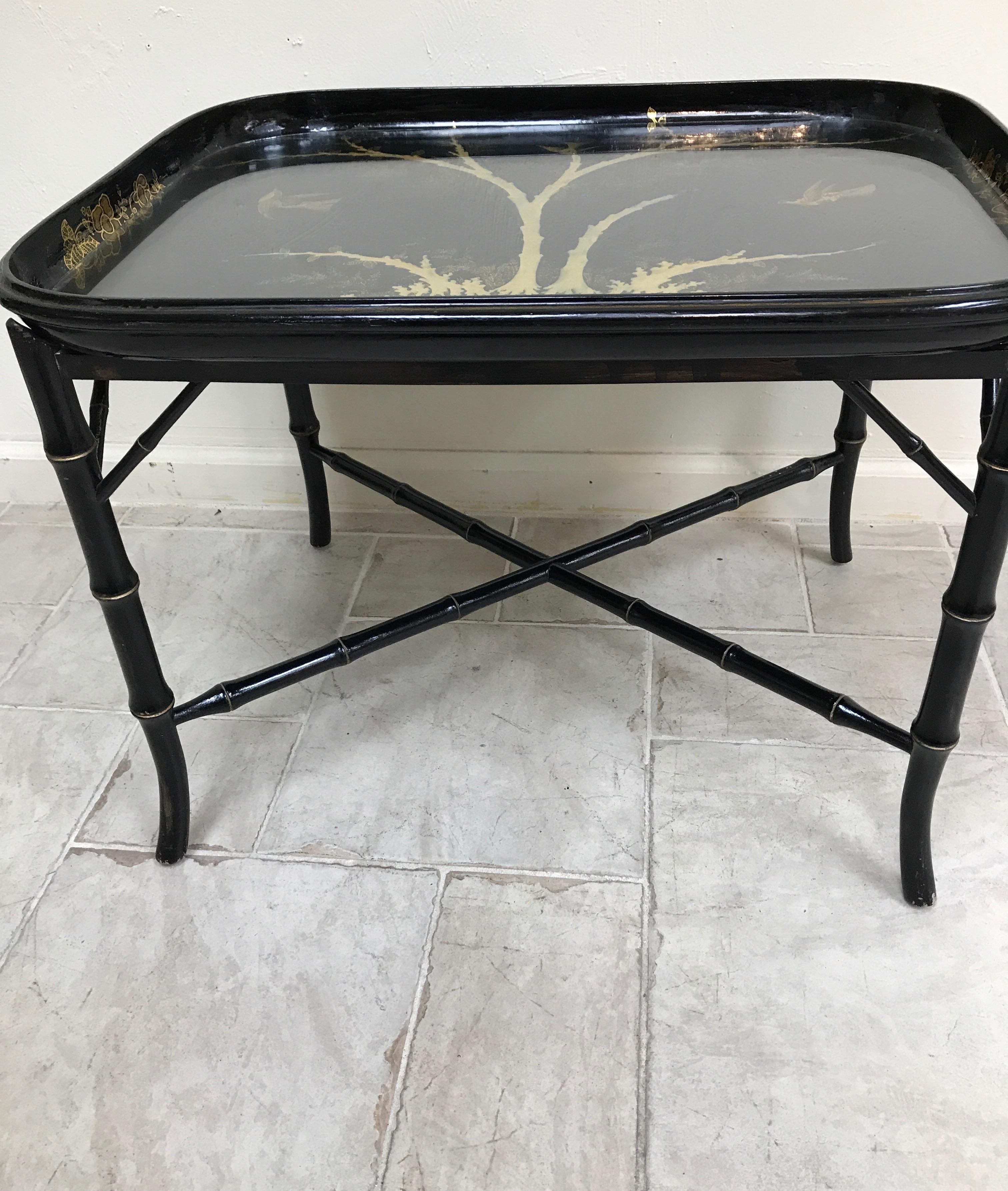 Antiker Pappmaché-Tisch in Schwarz und Gold. Der Sockel ist ein schwarz lackiertes Bambusimitat. Das Tablett ist mit einem Schutzglas versehen, das das vergoldete Baum- und Vogelmotiv abdeckt.