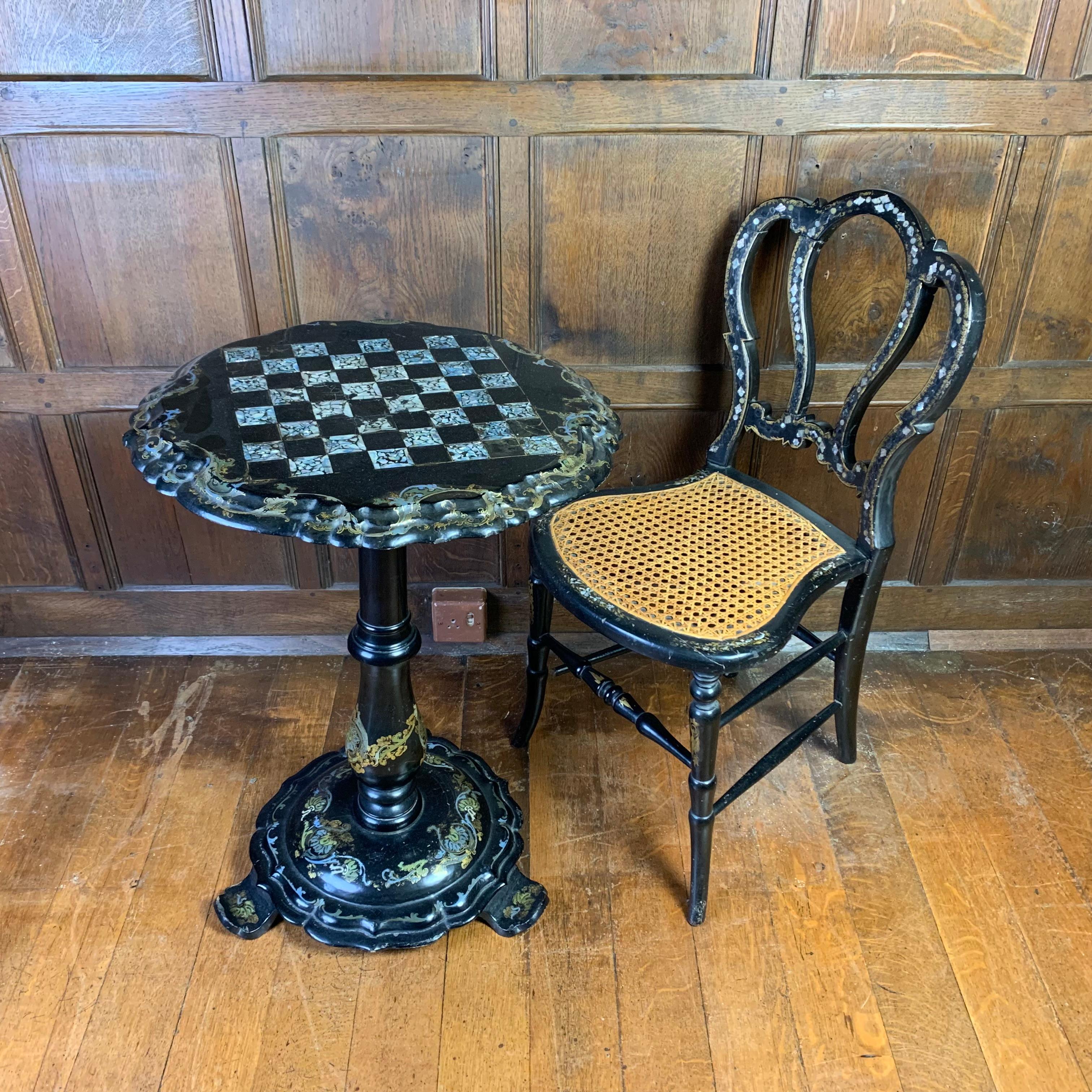 A fine quality 19th cenury papier mache tilt-top circular occasional table inset with a mother-of-pearl chess board to the top within a painted border of scrolling foliage. Raised on a vase-shaped stem and shaped circular base with three upturned
