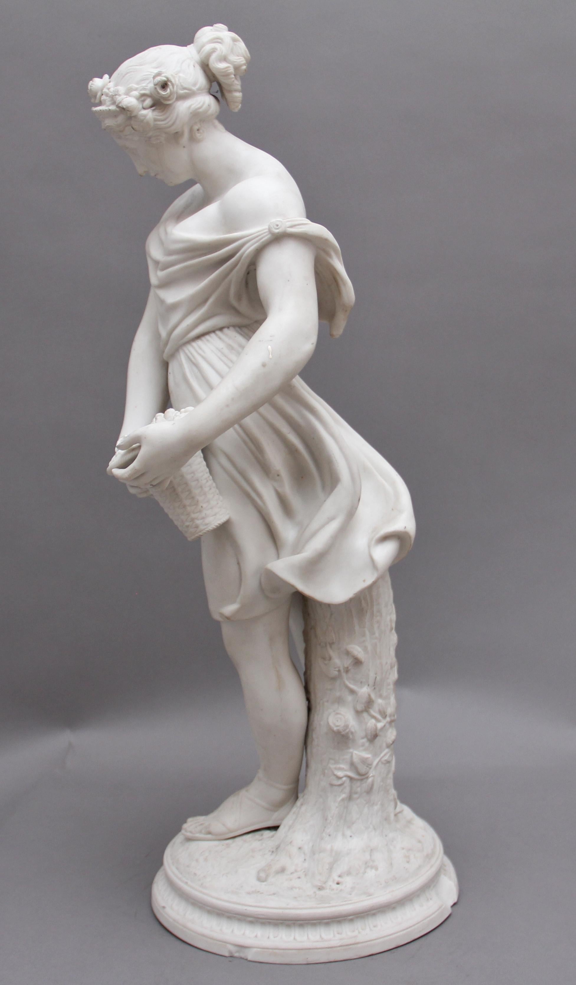 19th century parian figure of a flower maiden, the lady holding a basket of flowers and leaning on a floral log, wonderful detail all around. The base has some damage in a few places.. Circa 1850.
 