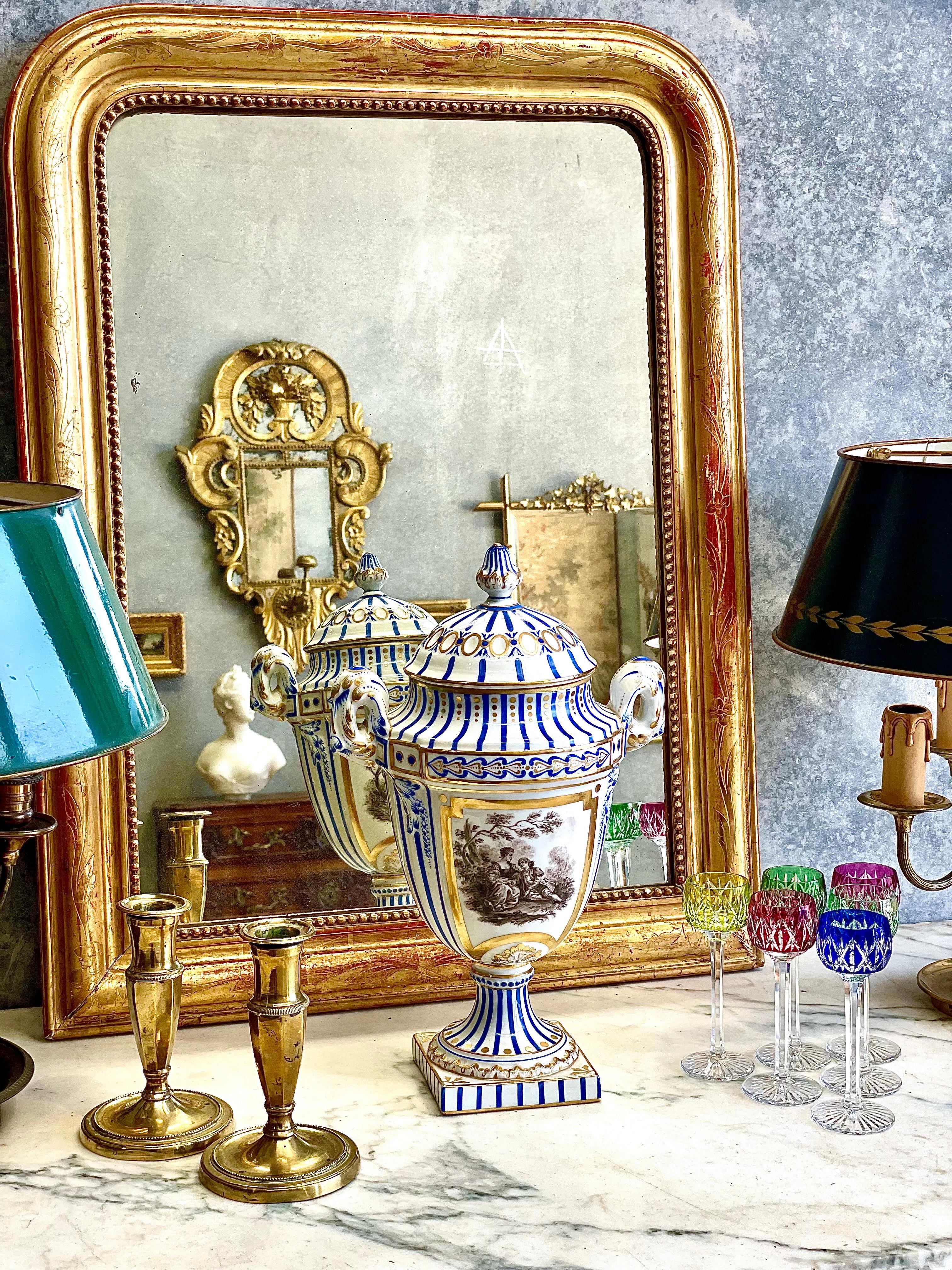 Elégante urne en porcelaine de Paris du XIXe siècle, d'une impressionnante prestance, finement peinte à la main en bleu cobalt, or bruni et tons sépia doux. Ce vase à couvercle présente le raffinement artistique typique des ateliers de porcelaine