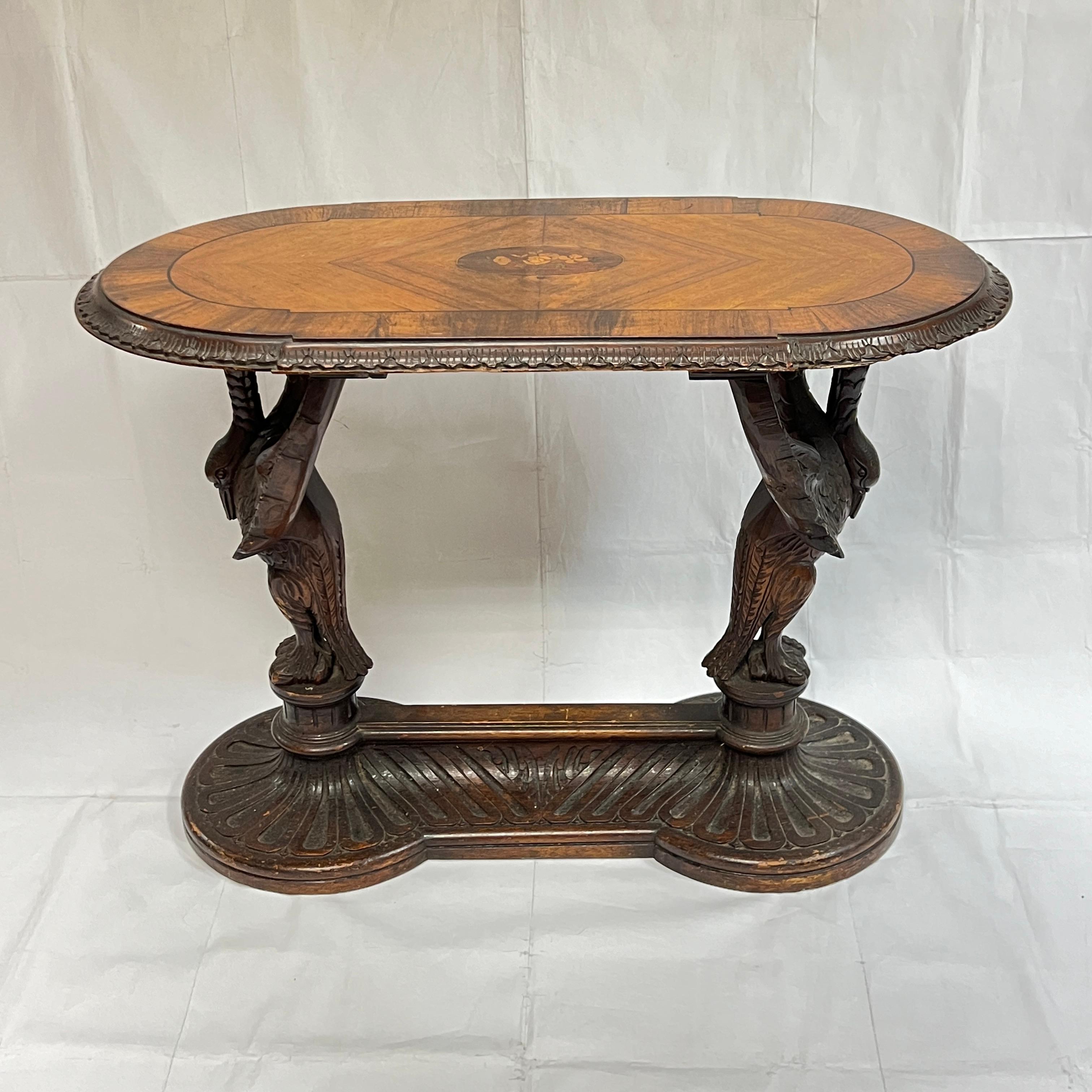 Beautiful antique oval shaped side table, 31 by 16 inches and 23 inches tall, with parquetry inlaid top with floral marquetry inlay at center, with finely carved swan-form legs emanating from an oval stretcher with carved gadrooning.  Apparently