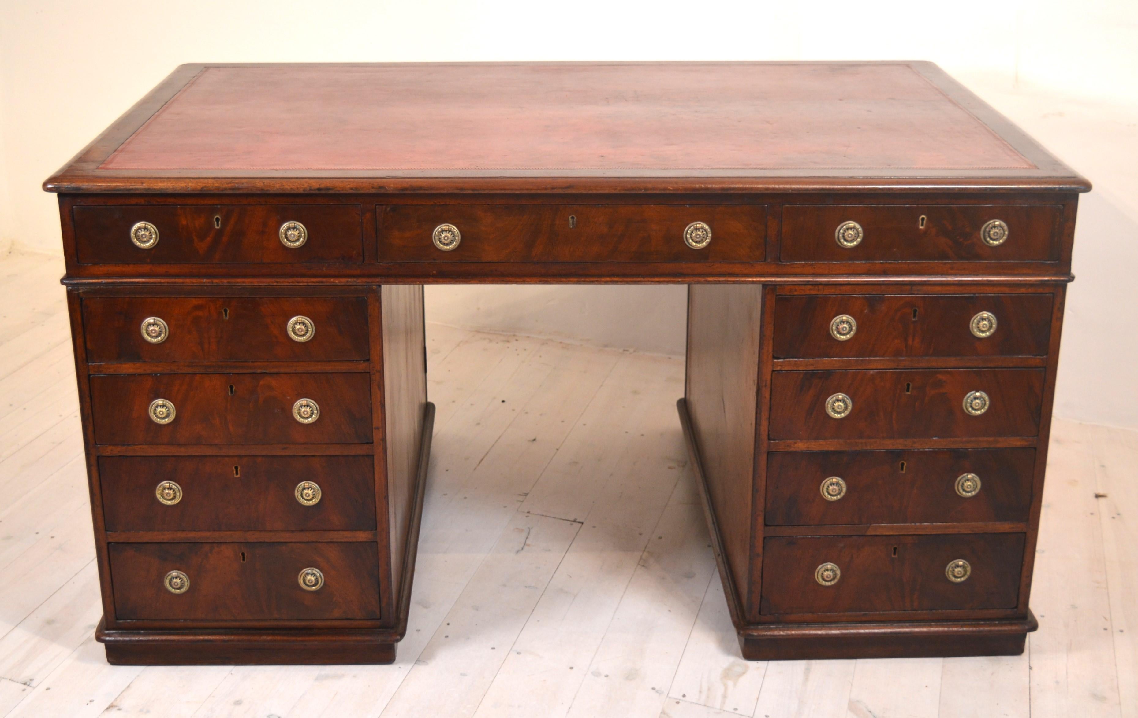 A 19th century mahogany partners desk of good colour with 14 drawers and two lockable cupboards. The drawers are Honduras mahogany and have a covering in  blue sugar paper, and the top has original red leather. The handles are in keeping but 
