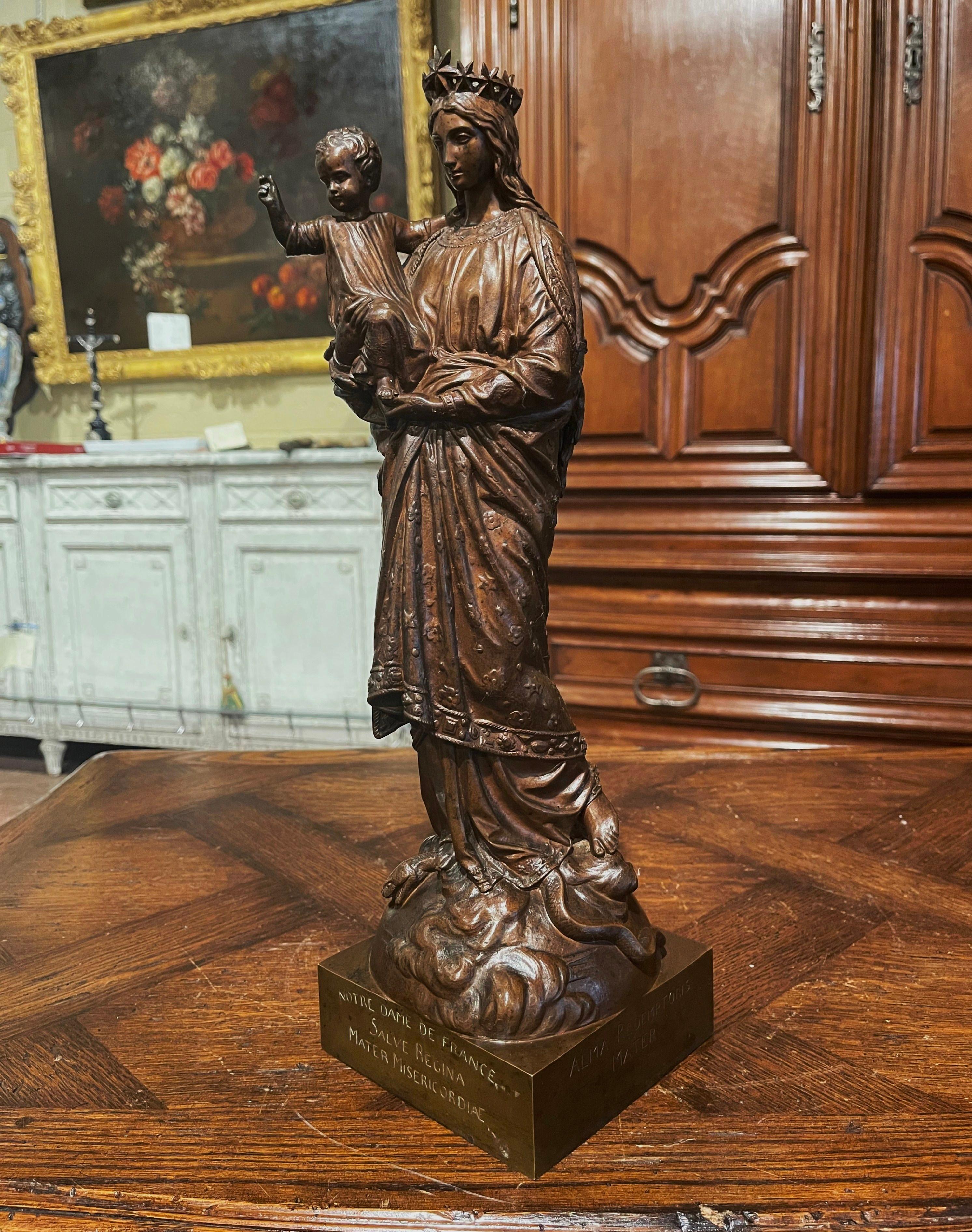 This elegant antique statue of the Virgin Mary and her Son, found in a chapel, was carved in Southern France, circa 1870. The large alluring bronze sculpture composition resting on a square base, features a crowned 