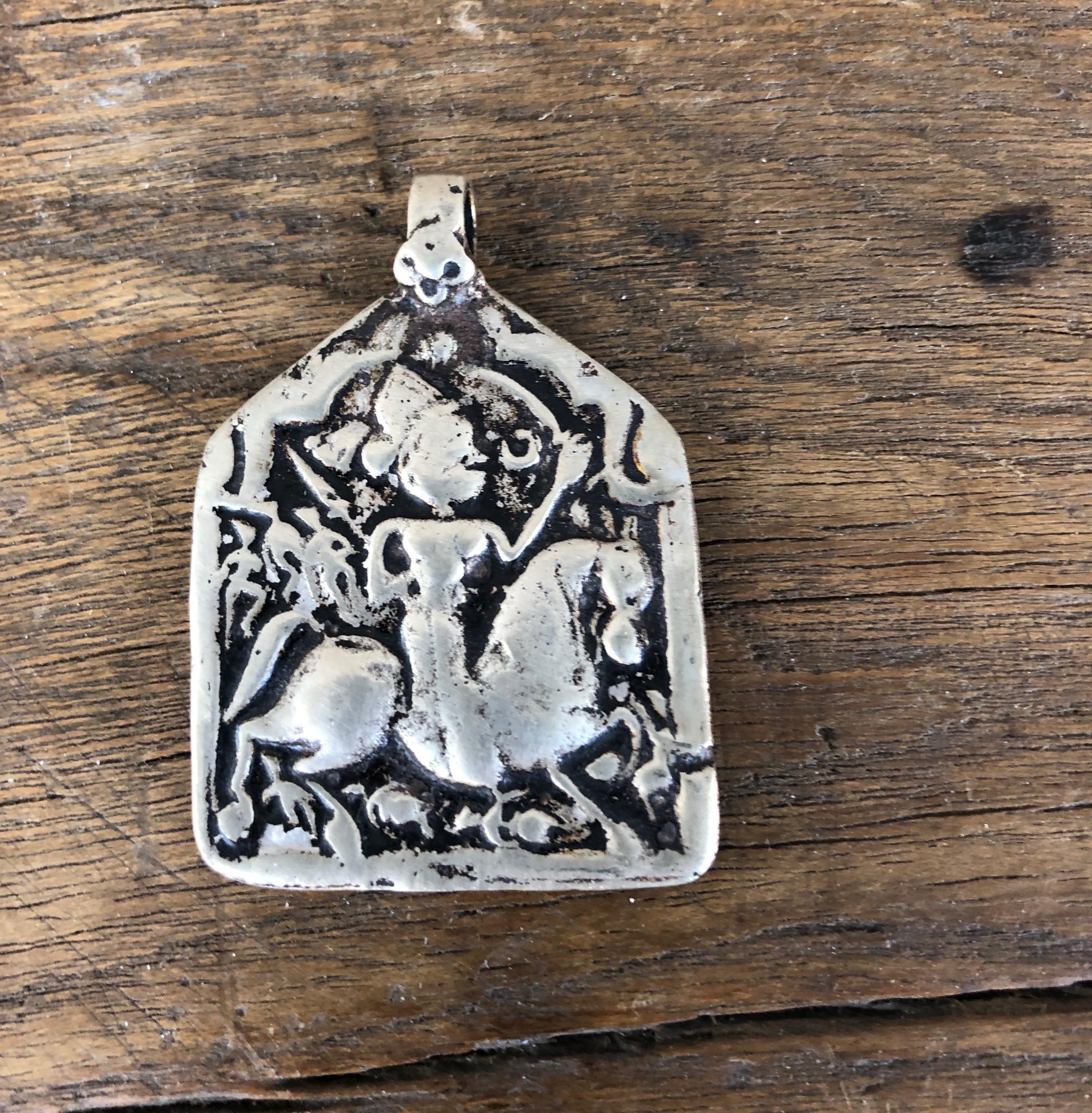 A stunning and rare 19th century amulet with detailed central imagery of a man astride a horse. This piece, from India, conveys it's age and history through the gorgeous patina created over several generations. Worn with a simple leather cord or
