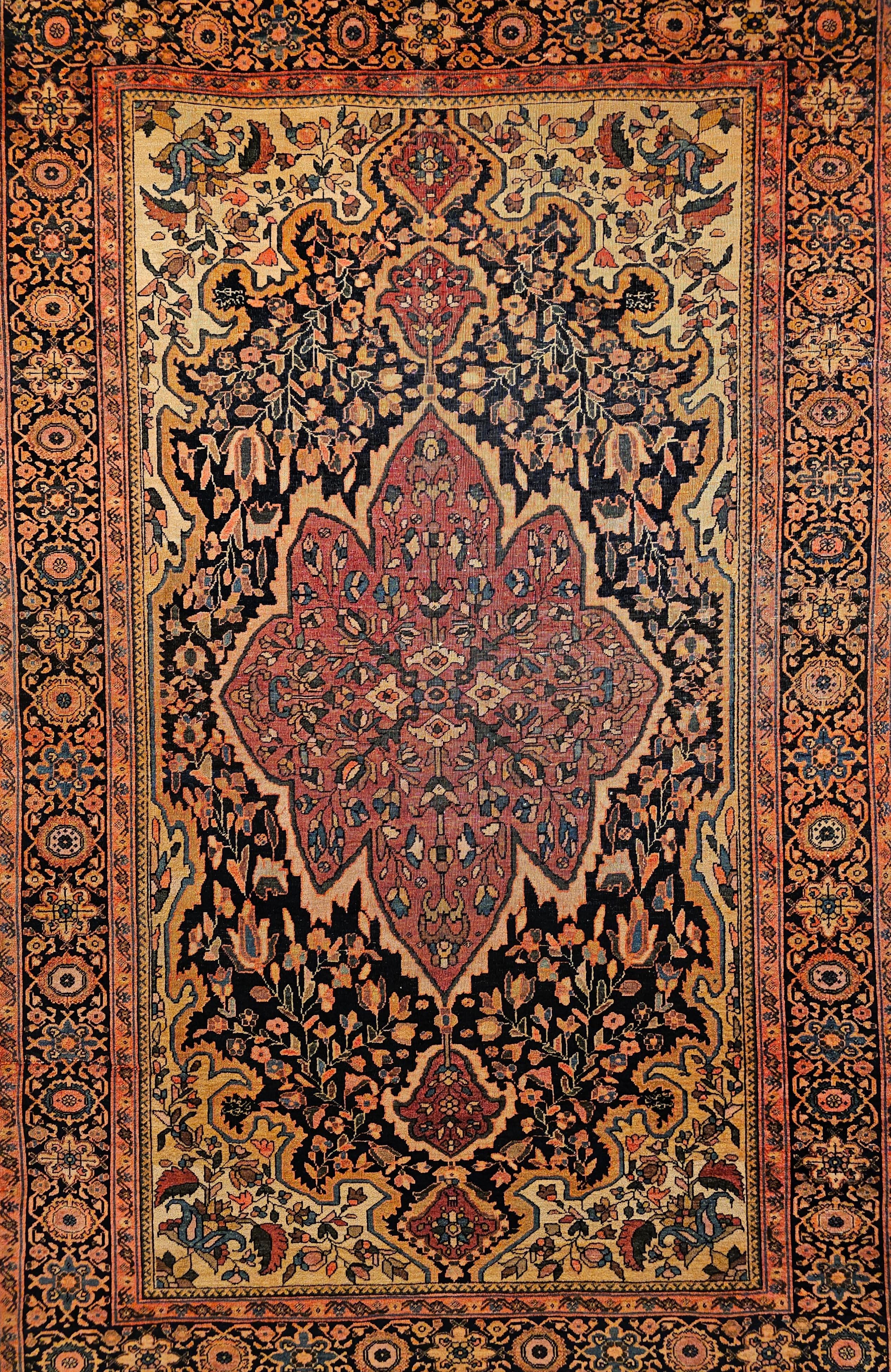 A 19th Century Persian Farahan Sarouk area rug in medallion design with floral pattern with navy blue, plum red, pale yellow, French blue colors.  The field has floral design set on a navy blue background.  There is a beautiful central medallion in