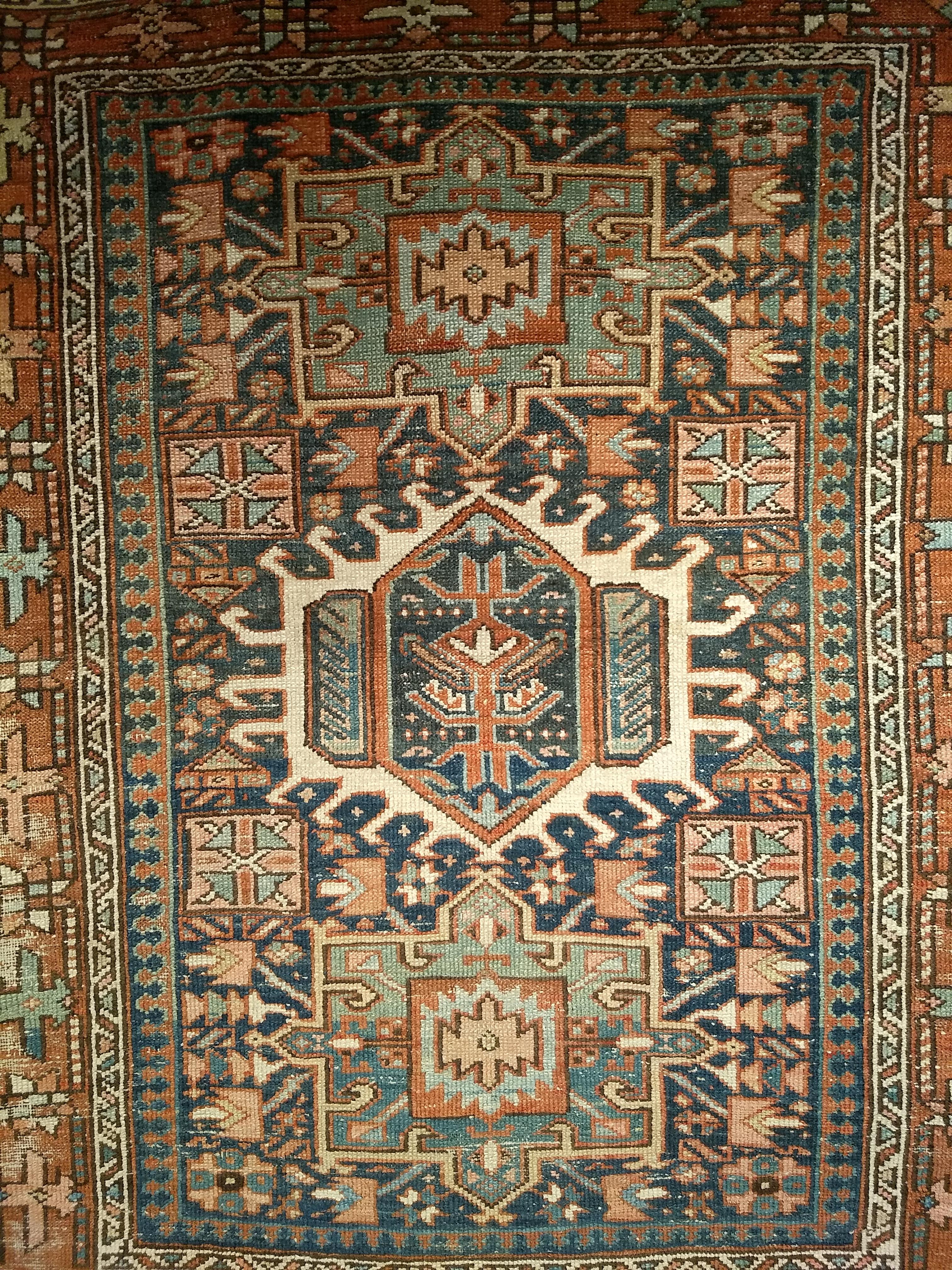 A beautifully preserved antique Heriz Karajeh area rug, handwoven in Northwest Persia circa the late 1800s. This piece features a refined geometric layout with three small medallions aligned vertically along the central axis, set against a deep navy