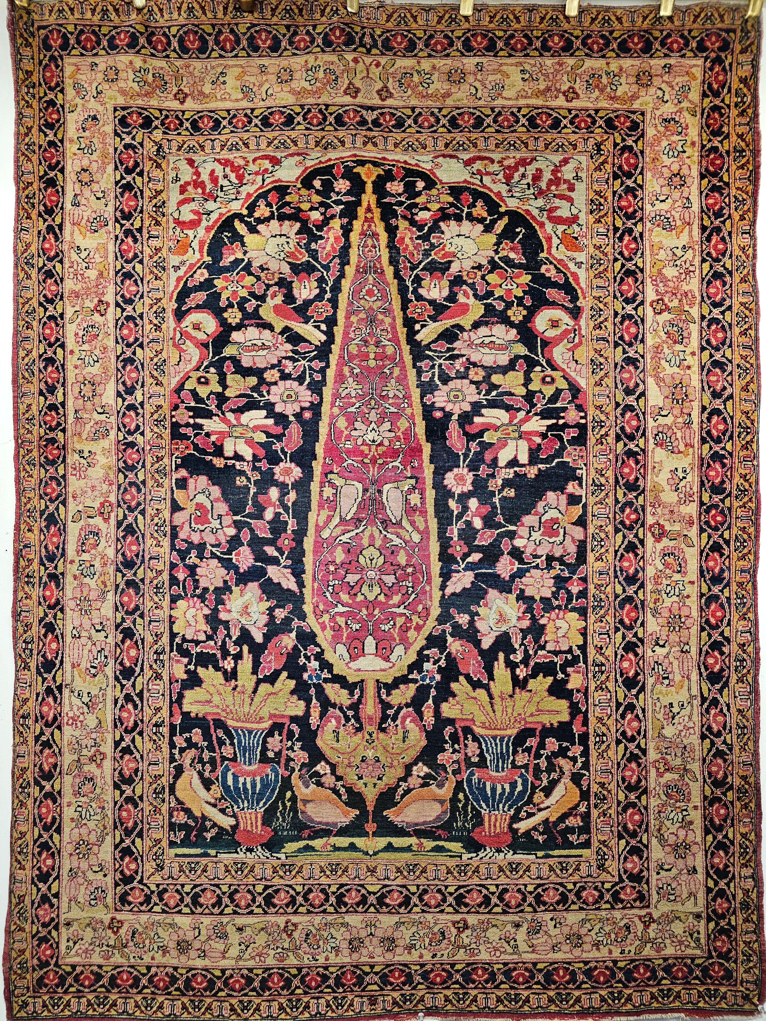 A beautiful Persian Kerman Lavar area rug with the “Tree of Life” design from the 4th quarter of the 1800s. The main field is midnight blue with a central cypress tree with a beautiful magenta color flanked by birds and flowering vases beneath a
