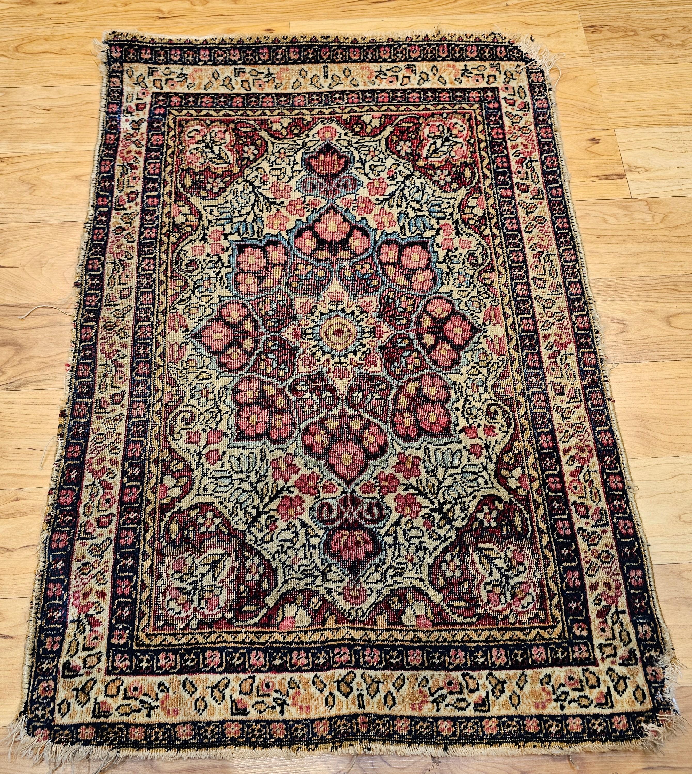  Gorgeously designed with a wonderful color palette Persian Kerman Lavar area rug in a large format floral pattern from the late 1800s. The main field is in an ivory color with a central medallion in navy or midnight blue with the corner spandrels