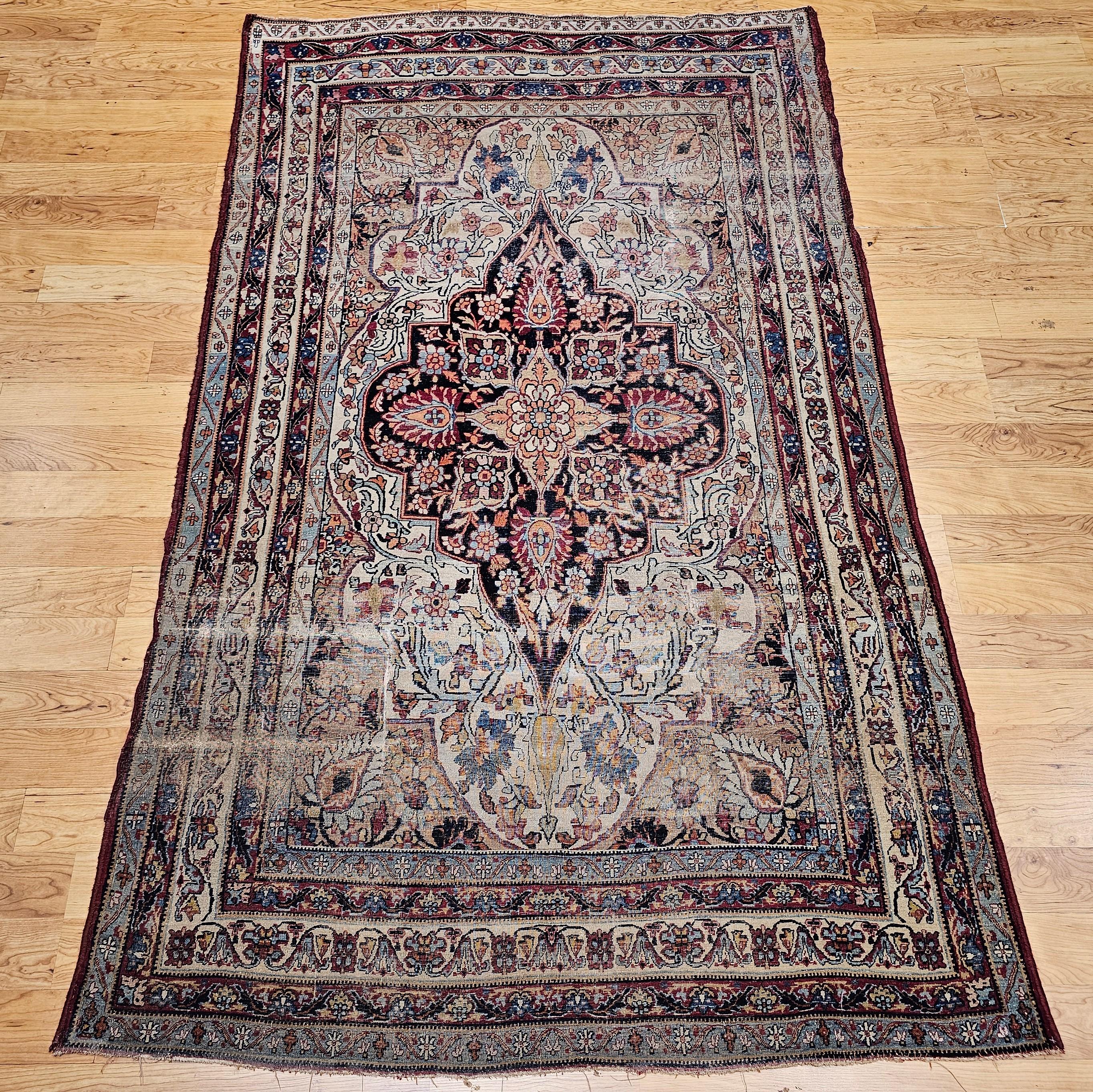 Truly a masterpiece of design and colors!  Beautiful Kerman Lavar rug with a central medallion with a large format floral design from the late 1800s. The main field is in an ivory color with a central medallion in navy blue. The rug has accent