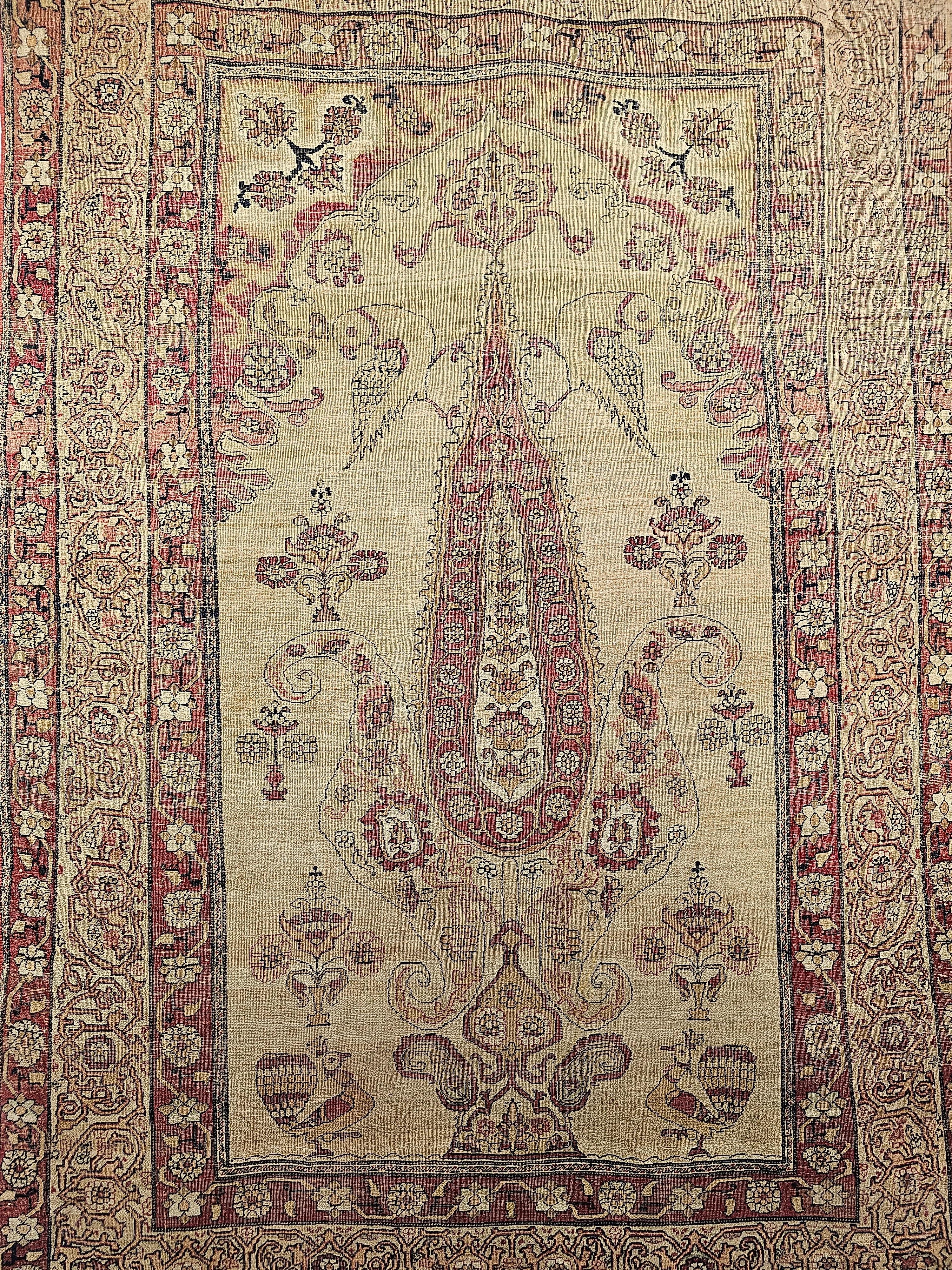 A beautiful Persian Kerman Lavar pictorial area rug with the “Tree of Life” design from the 4th quarter of the 1800s.  The main field is light tan or camel with a central cypress tree with a beautiful magenta color flanked by birds (parrots) and