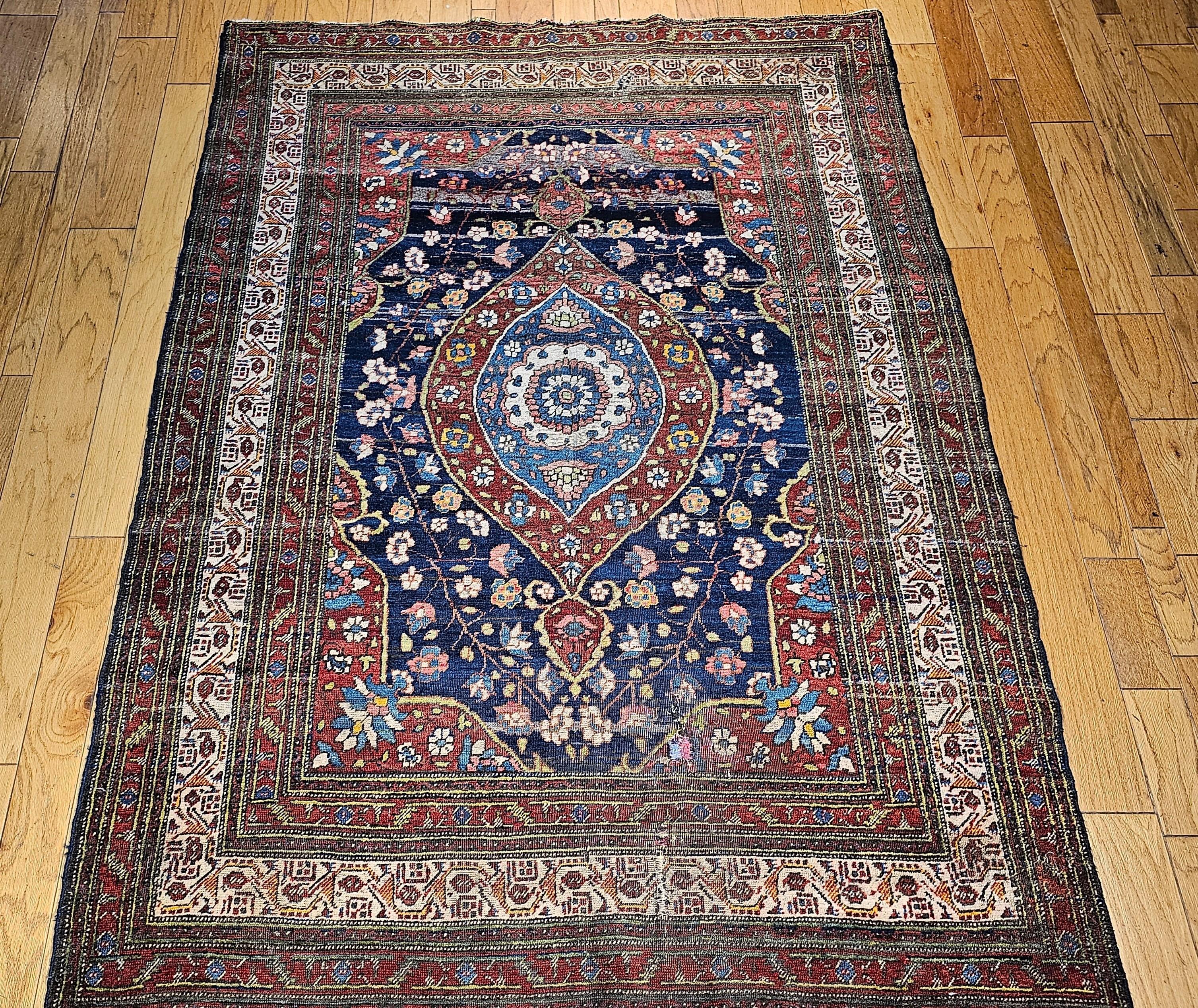 19th Century Persian Kurdish room size rug in a medallion pattern in navy, French  blue, green, yellow, and red.   The Kurdish village rugs from northwestern Persia have a large elongated diamond medallion that covers a big portion of the field and