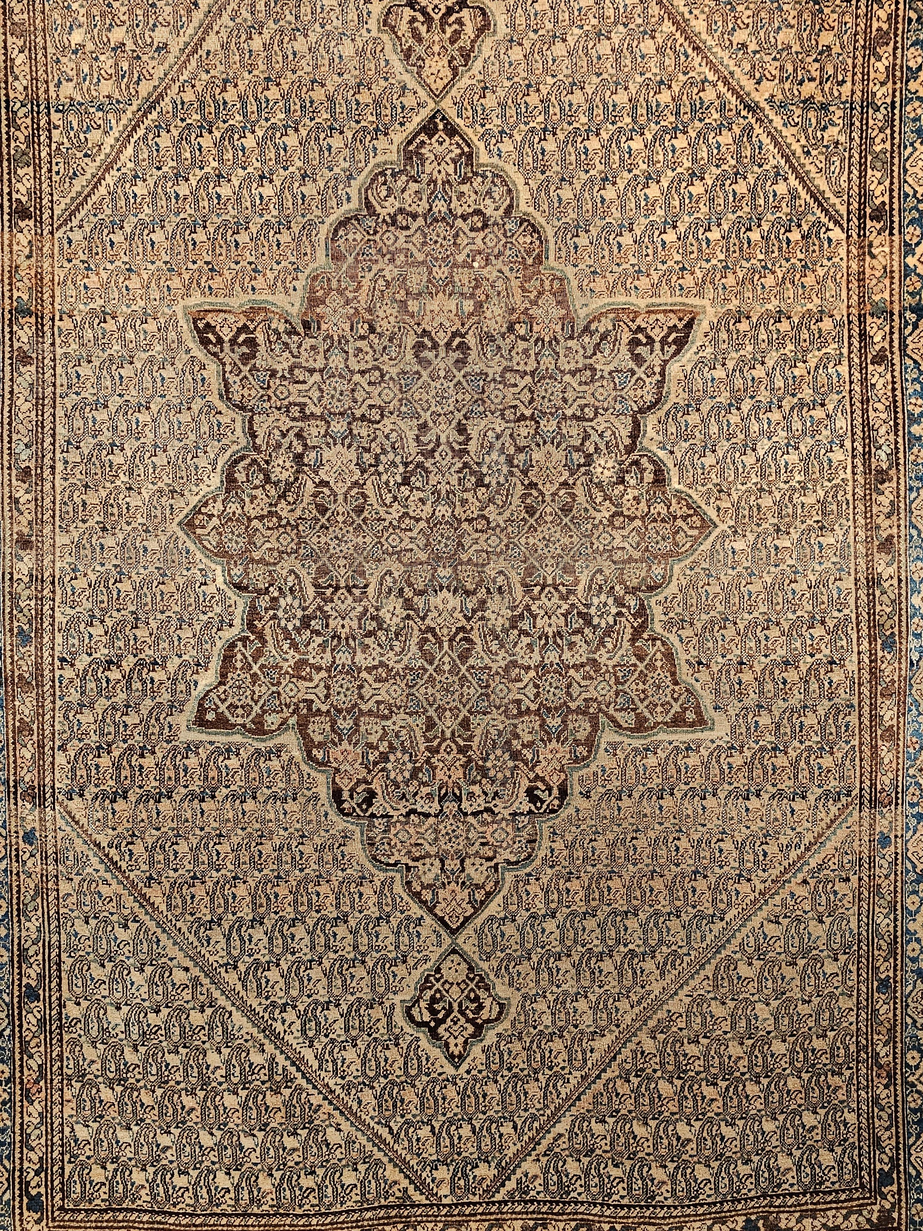 A Persian Senneh area rug in an allover paisley pattern in a pale latte, chocolate brown, and French blue colors was very finely woven in a Kurdish village in the Western Persia around the 3rd quarter of the 1800s. The beautiful Senneh has a