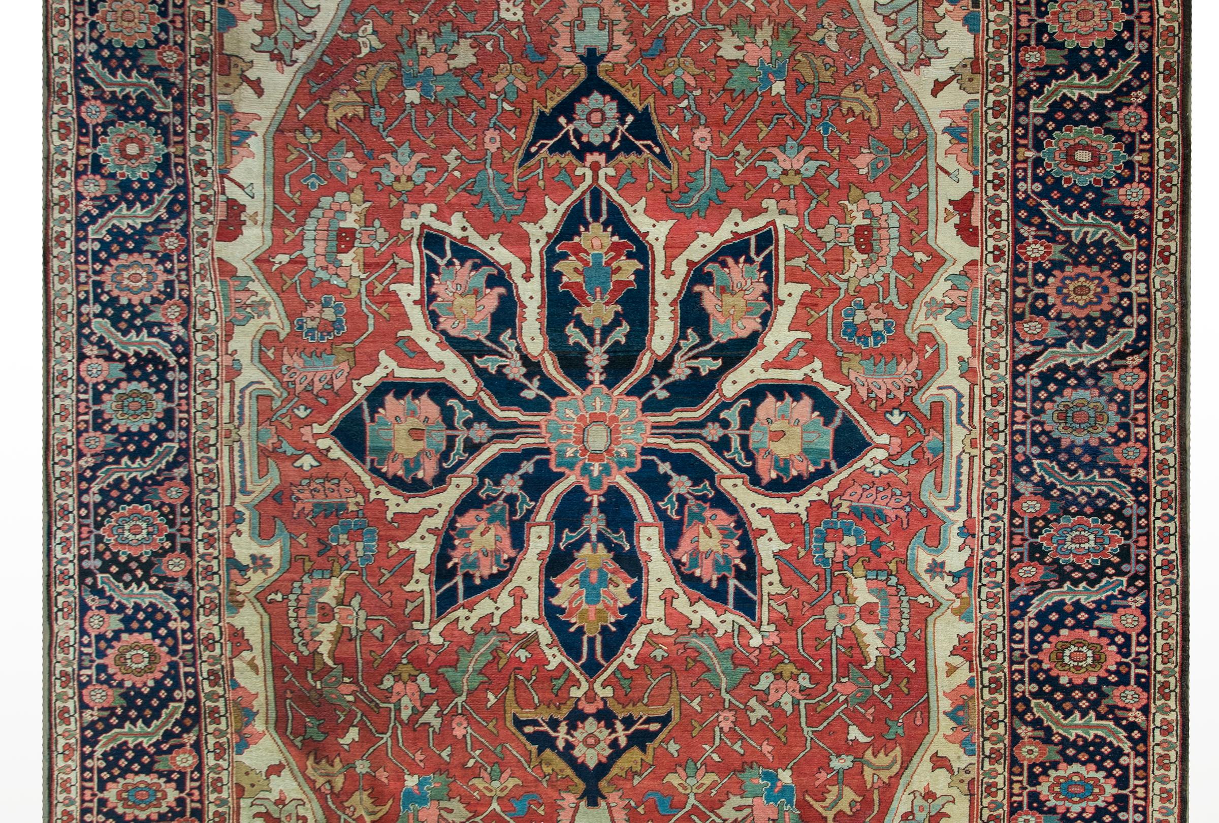 A magical and mesmerizing late 19th century Persian Serapi rug with the most beautiful central floral medallion with large-scale flowers and leaves woven in abrash indigos, pinks, crimsons, creams, and golds, and set against a field of more flowers