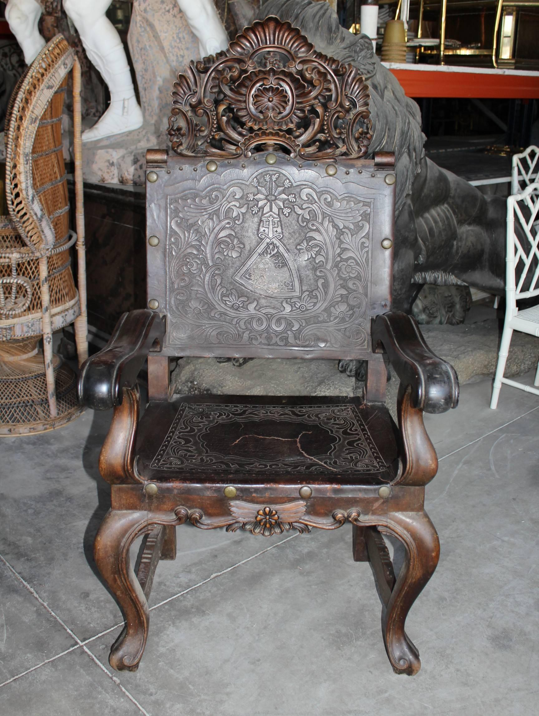 19th century Peruvian hand-carved chestnut armchair with carved crest and worked leather backrest and seat.