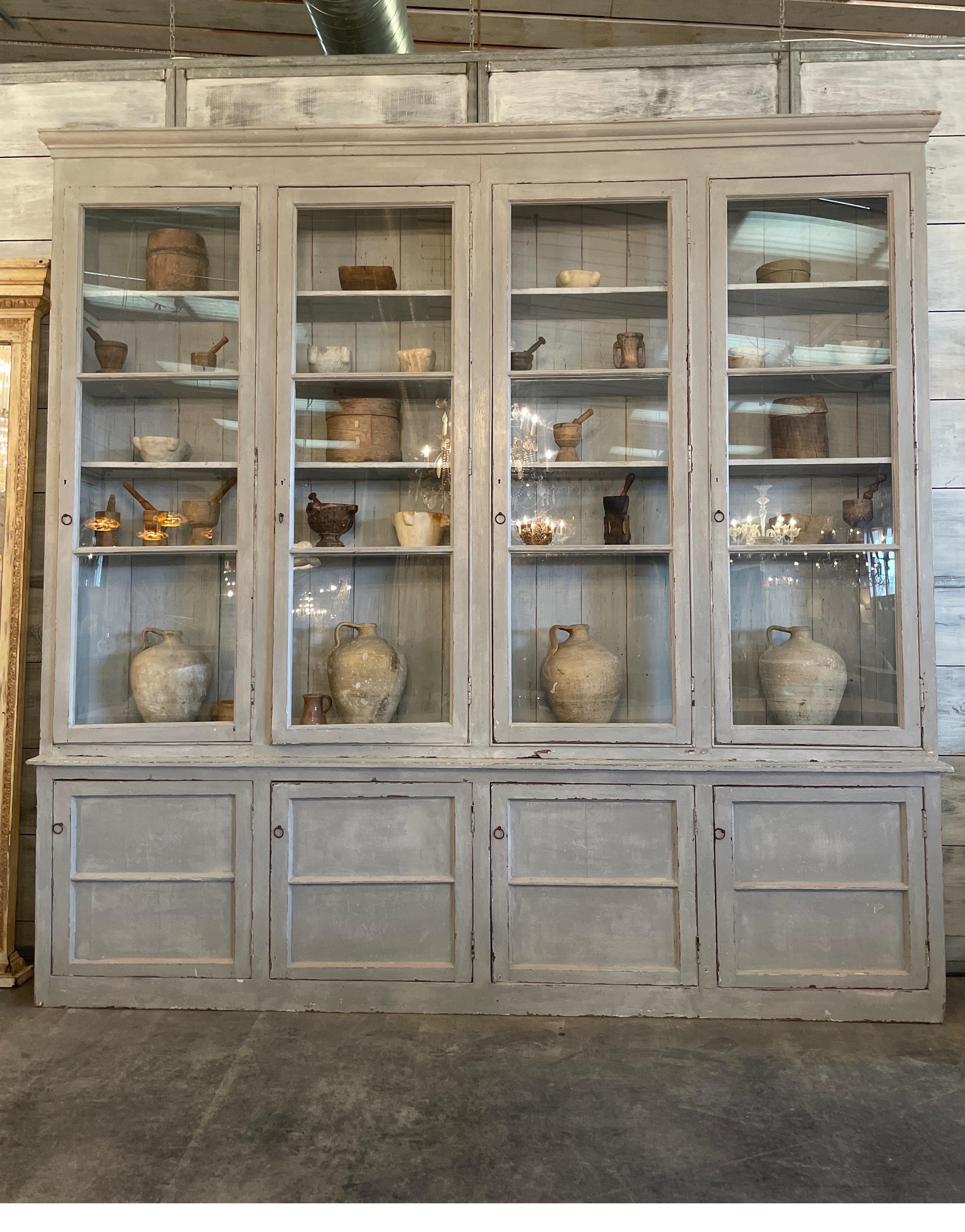 This is a creamy gray painted Portuguese cabinet used in a pharmacy from the 1800s. Original paint was a dark reddish brown. This is a newer paint that is very decorative.  Dimensions are 126 5/8 w x 15 5/8 d x 10’3” tall. It has lots of storage and