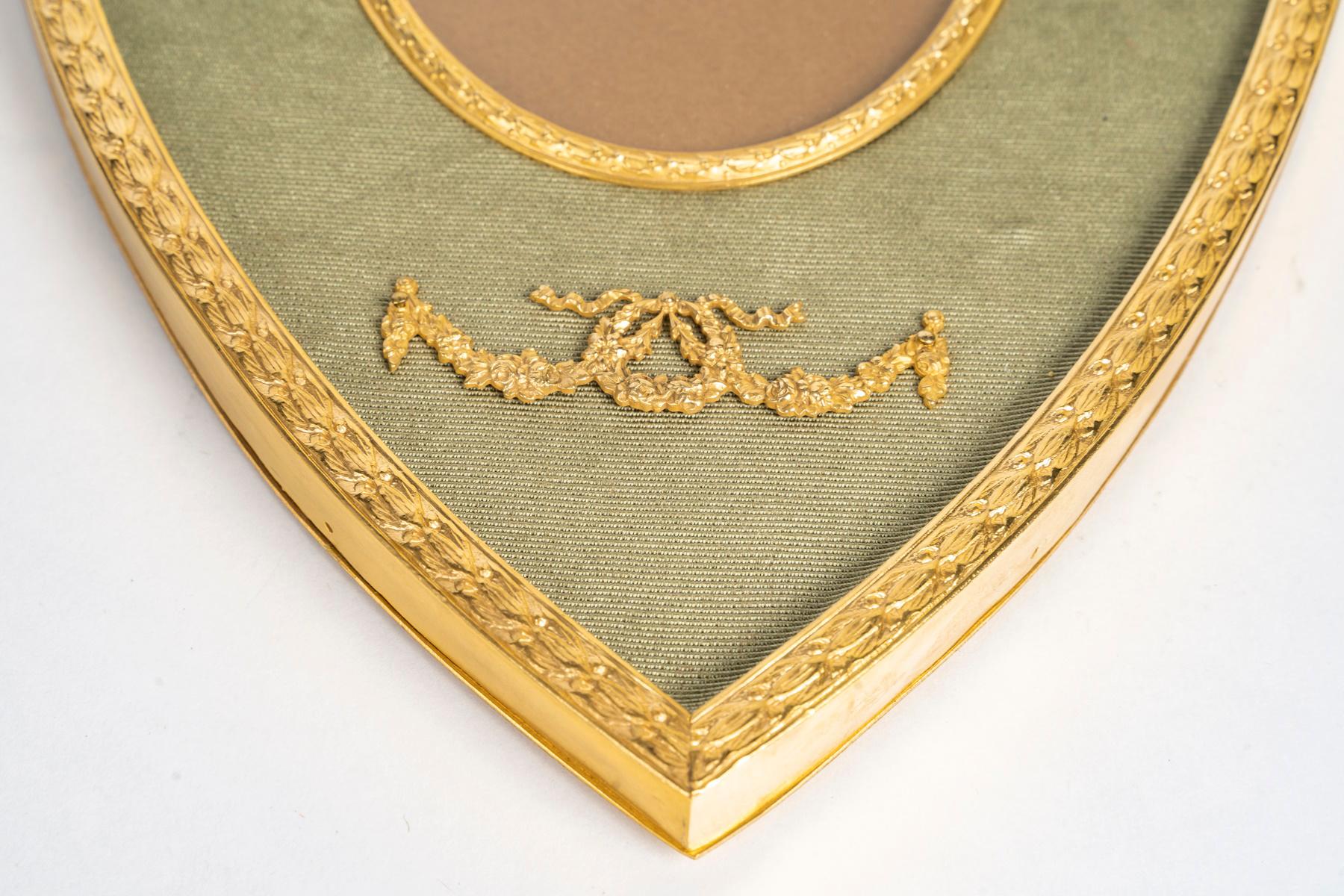 Cornice fotografica del XIX secolo a forma di stemma, realizzata in ottone dorato e tessuto verde, risalente all'epoca di Napoleone III.

Cornice fotografica del XIX secolo a forma di stemma, risalente all'epoca di Napoleone III, realizzata in