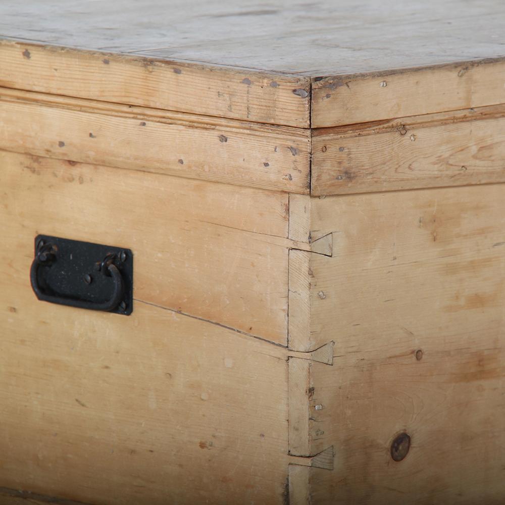 A simple rustic English Victorian pine blanket box or trunk with exposed dovetail joinery to the corners and original metal handles and hinges.
 