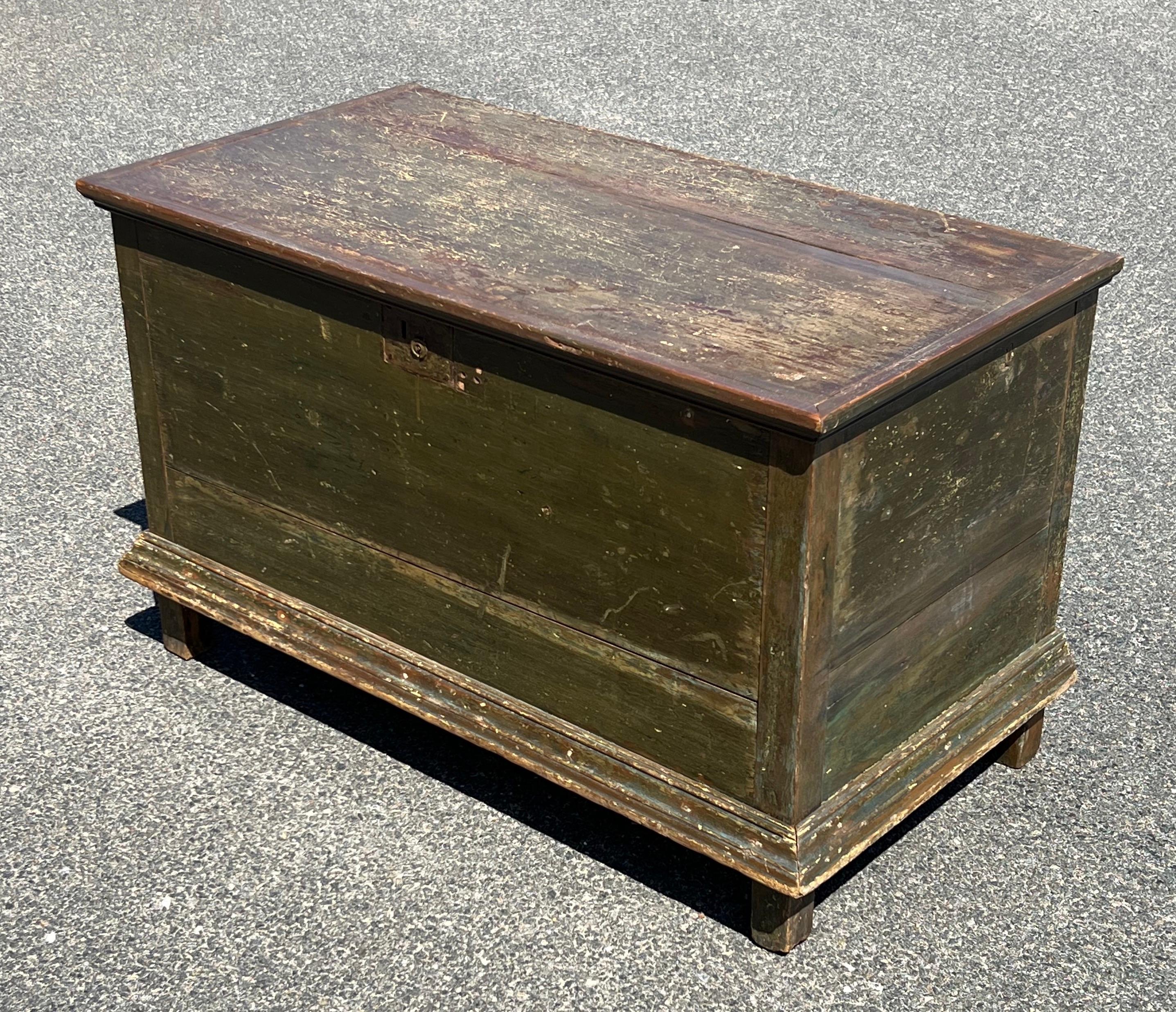 19th century blanket chest, Pine construction and original olive green paint. Top with iron strap hinges on interior and two applied ribs for strengh. Keyless iron lock on front and applied stepped molding at base.