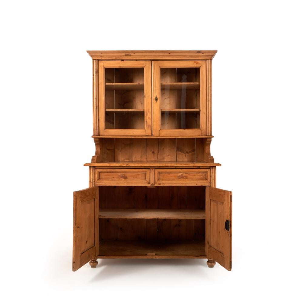 A simple pine buffet or kitchen cabinet, the base with cabinets and drawers, the upper cabinet with glass doors above a serving / work surface.
This useful 19th century piece is nicely-proportioned, and has a warm honey-colored waxed patina.