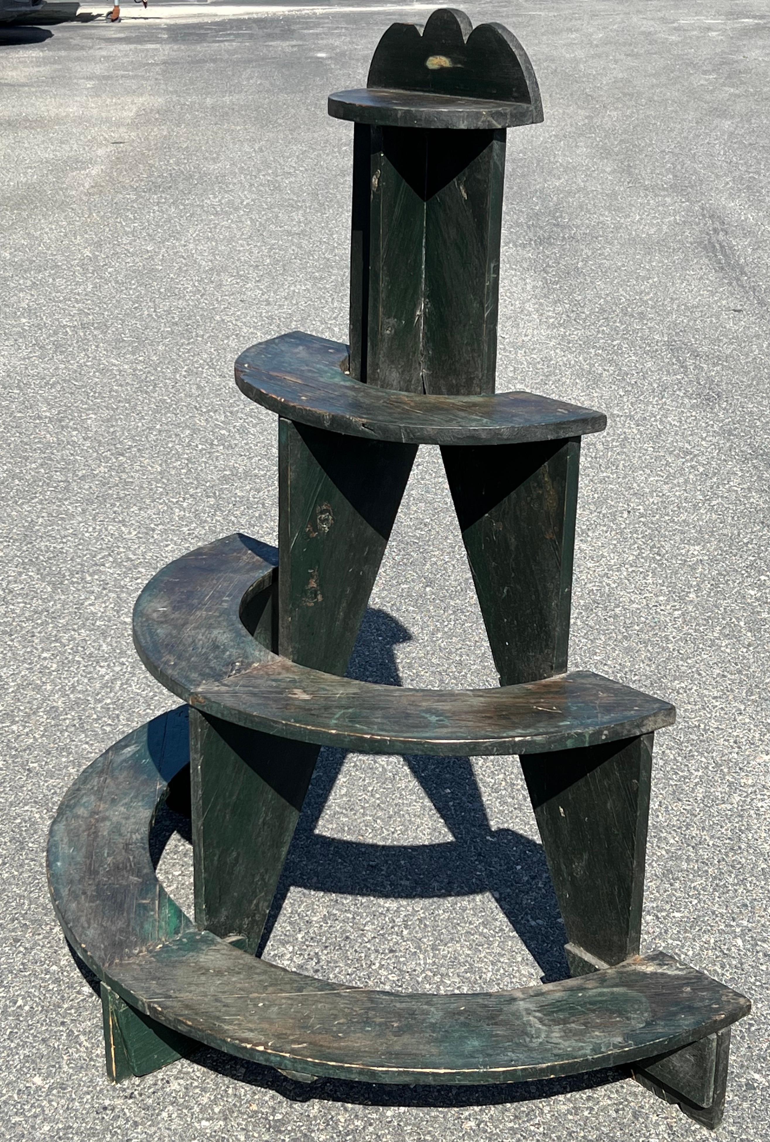 Four tiered plant stand in original green paint with patina and wear from use.  Sturdy construction and overall demi-lune form.