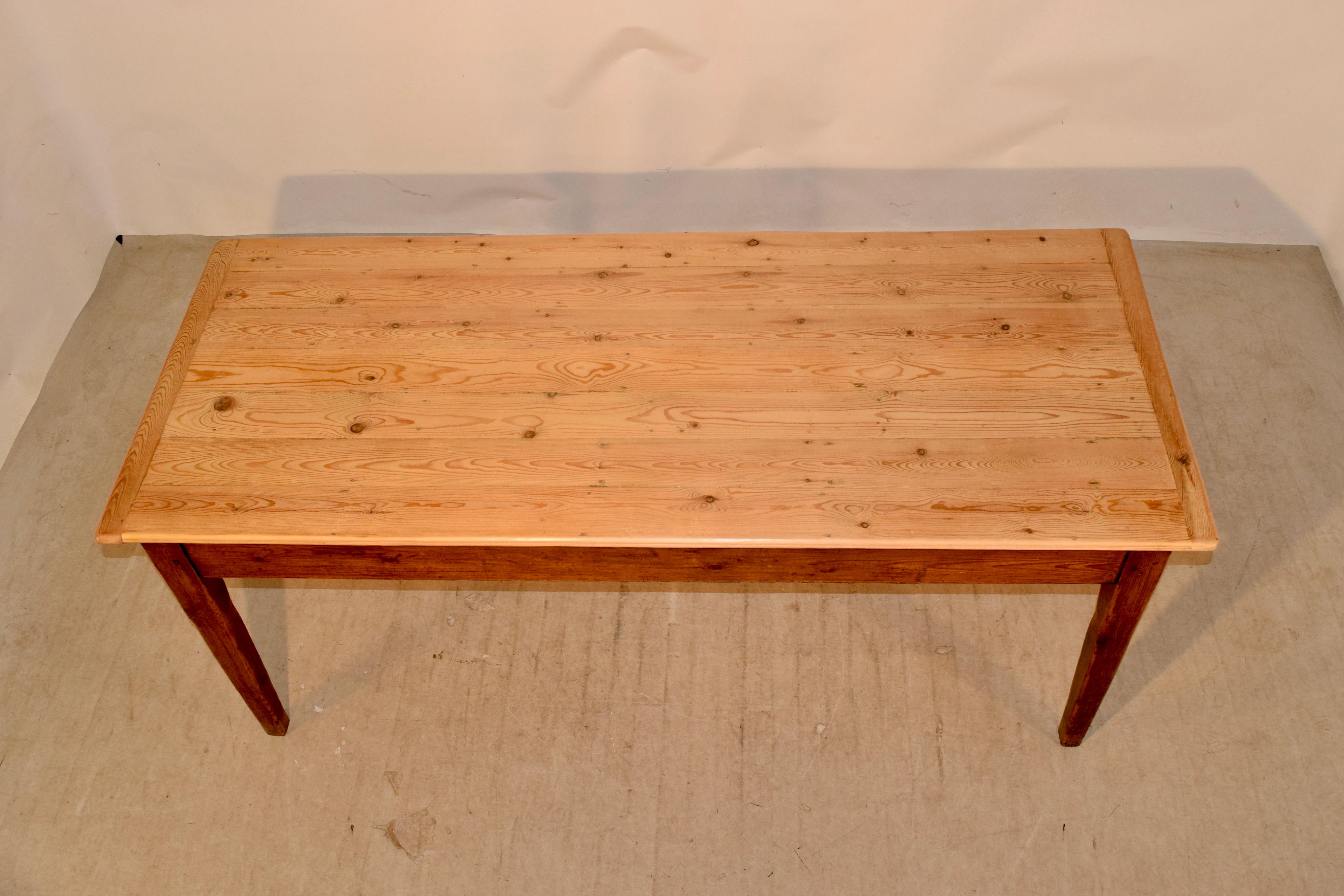 19th Century French farm table with a scrubbed plank top which has banded ends. The top is supported on a pitch pine base with tapered legs. Simple and elegant. The apron measures 23.5 inches in height.