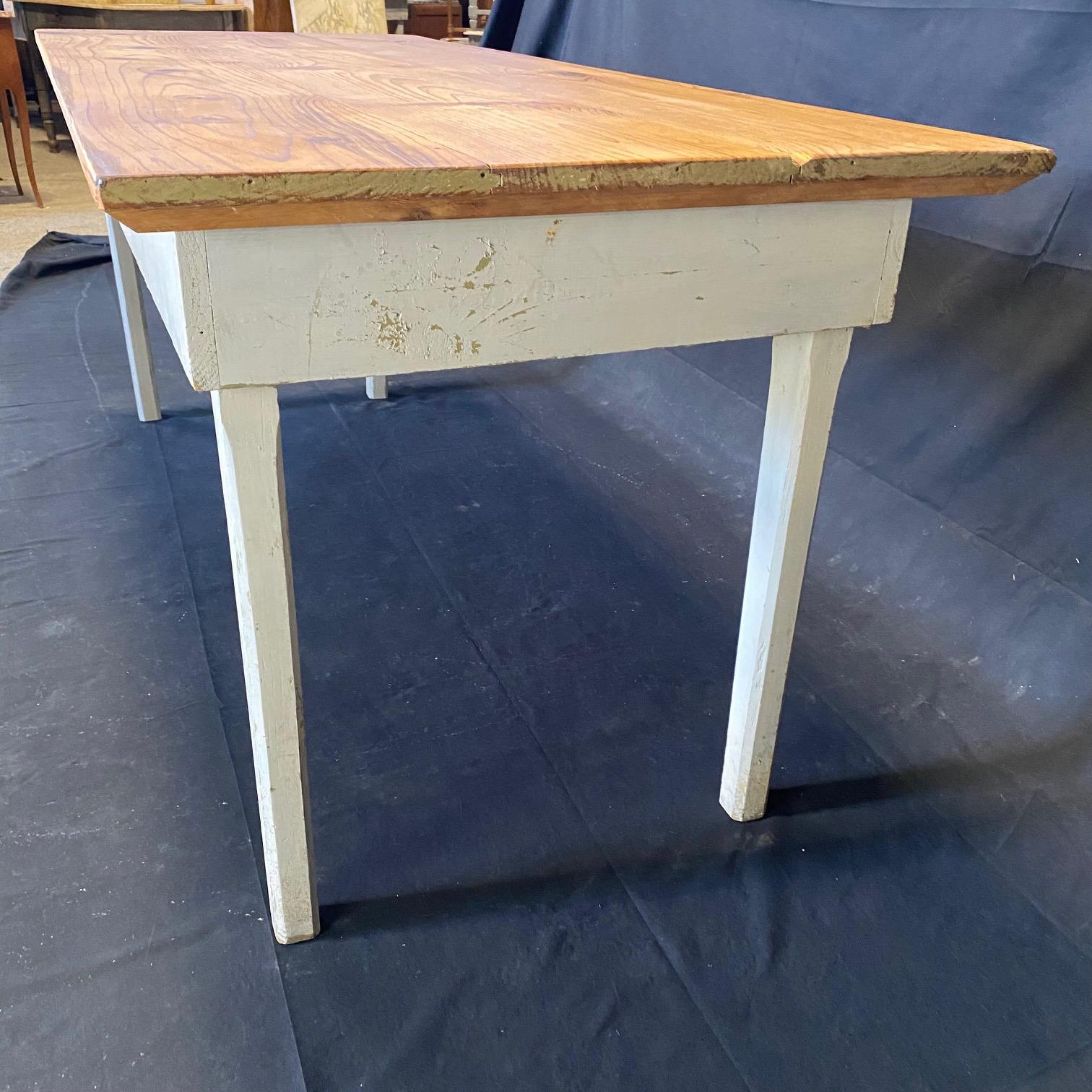 This classic primitive style dining table in the farmhouse style is from an early Grange in Maine. Used since the 1800s to hold town meetings, it has been restored beautifully, yet retains its original paint on the body. All legs can be released and