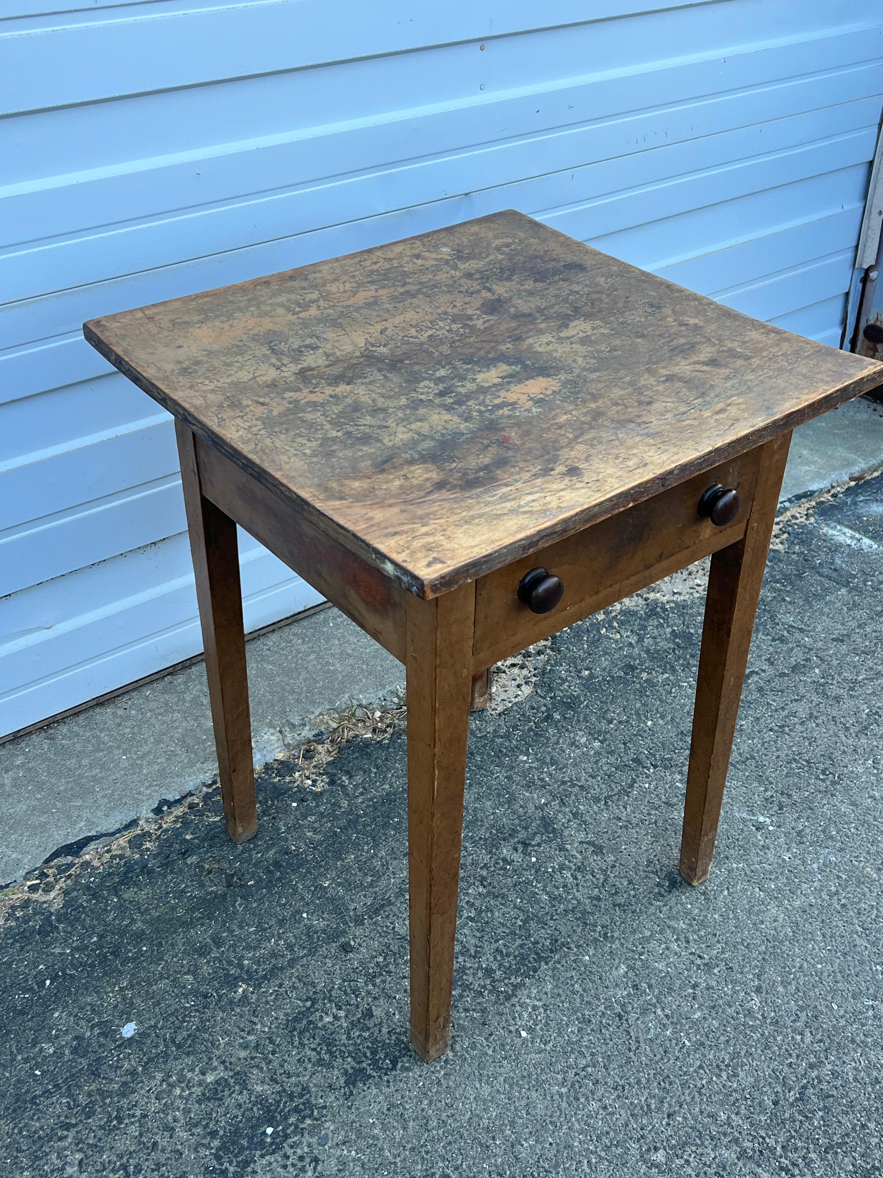 19th century Pine side table with slightly bowed (from age) single board top above drawer with two black painted, turned knobs.  On tapered legs.  