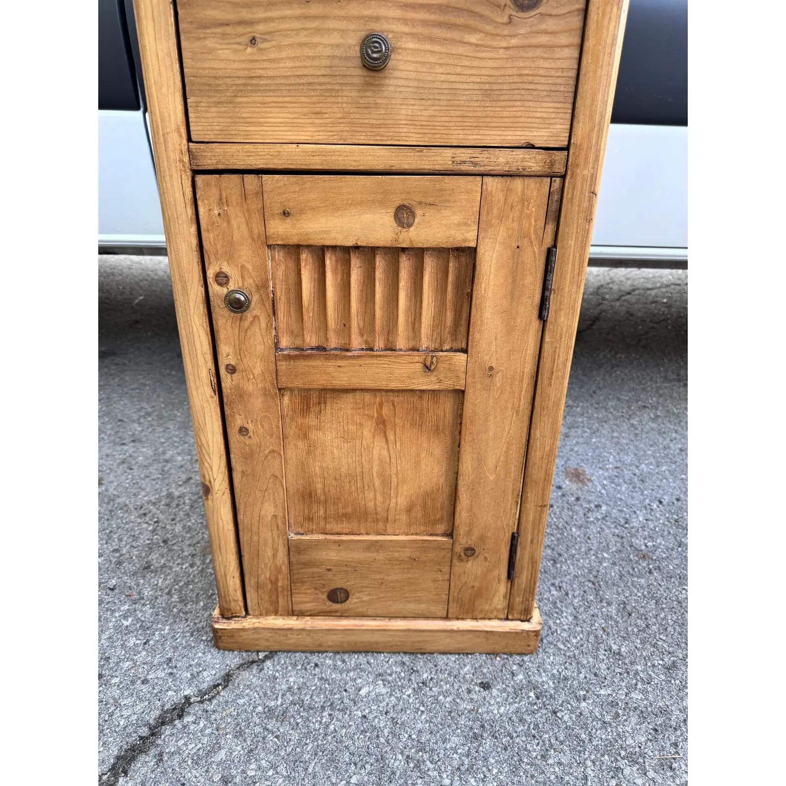 Questo è un bellissimo tavolino inglese! Questo tavolo in legno naturale ha un cassetto e un'anta con scaffali. Il pino è molto popolare in questo momento in tutte le sue forme e questo non fa eccezione, con un tono bellissimo e una patina