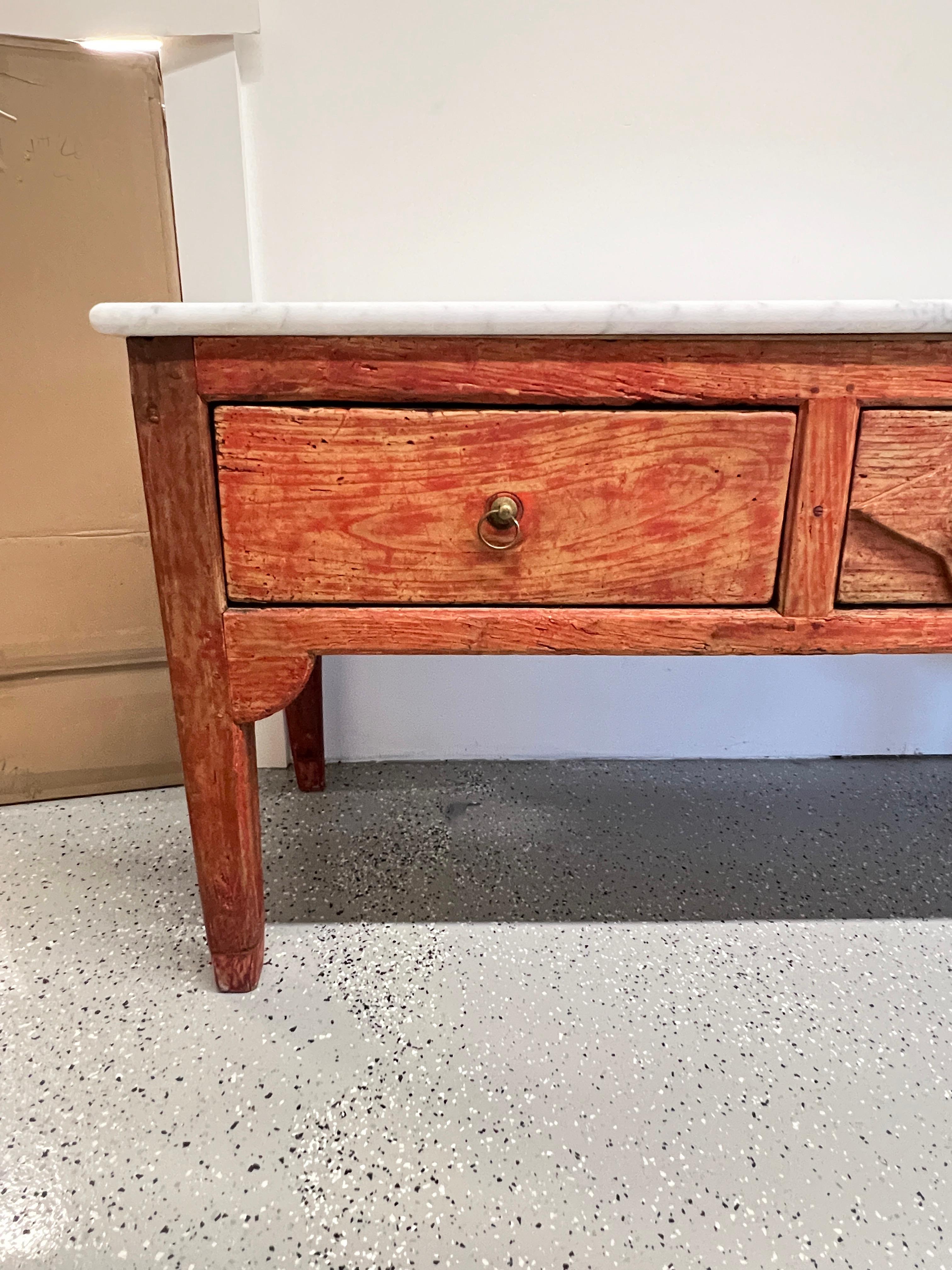 Aparador o mesa de fregadero de pino del siglo XIX procedente de los Pirineos orientales del Southern France, provisto de una encimera de mármol. Se alza sobre robustas patas achaflanadas con ménsulas adosadas en su color rojo original; construcción