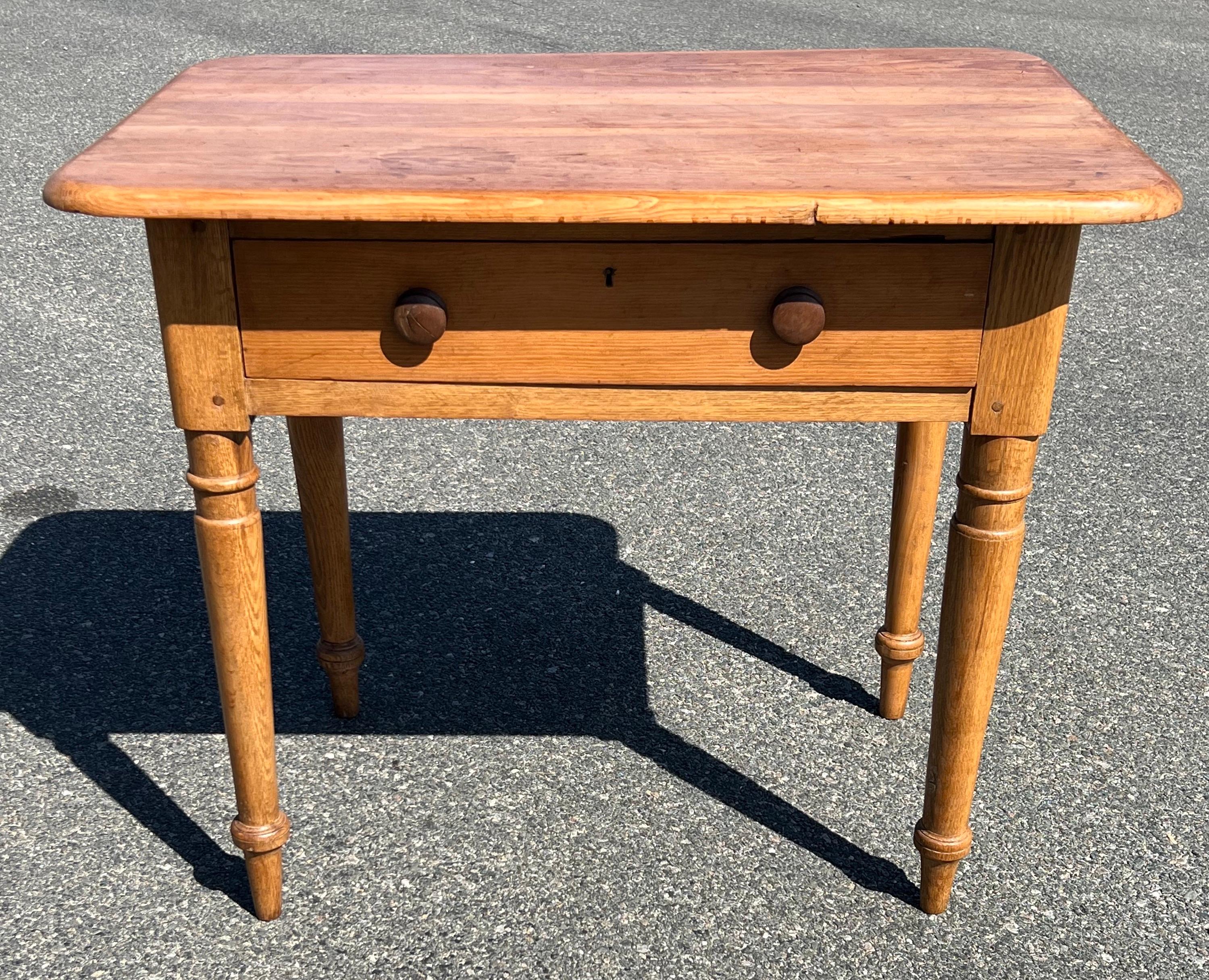 19th century Pine side table in natural finish. Thick top with rounded corners and good overhang. Large single drawer with two turned wooden knobs and carved key hole (no key). Overall pegged construction.