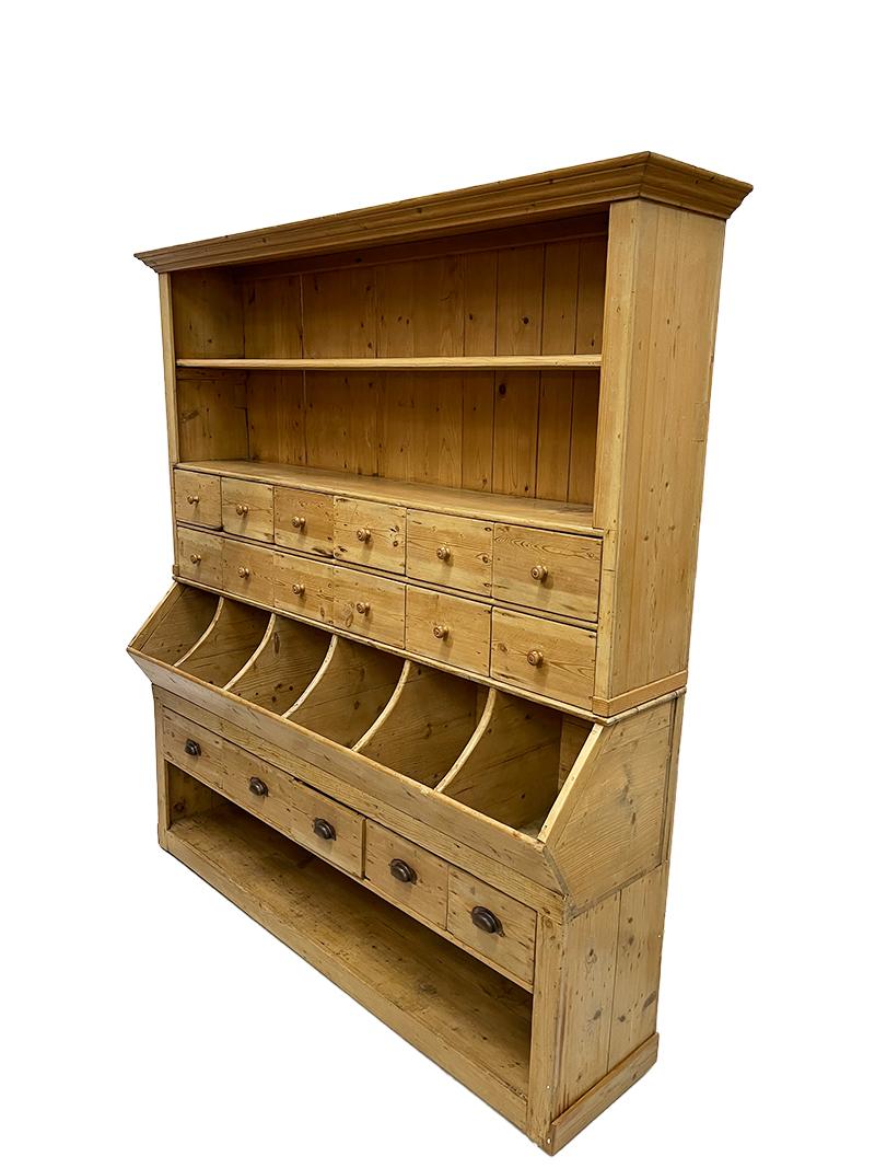 19th Century pine store display cabinet.

A pine display cabinet consisting of 2 parts. The lower part consists of an open space and above it 5 drawers. and 6 open bins. The upper part consists of 12 drawers and 2 open compartments with 1 shelf. It