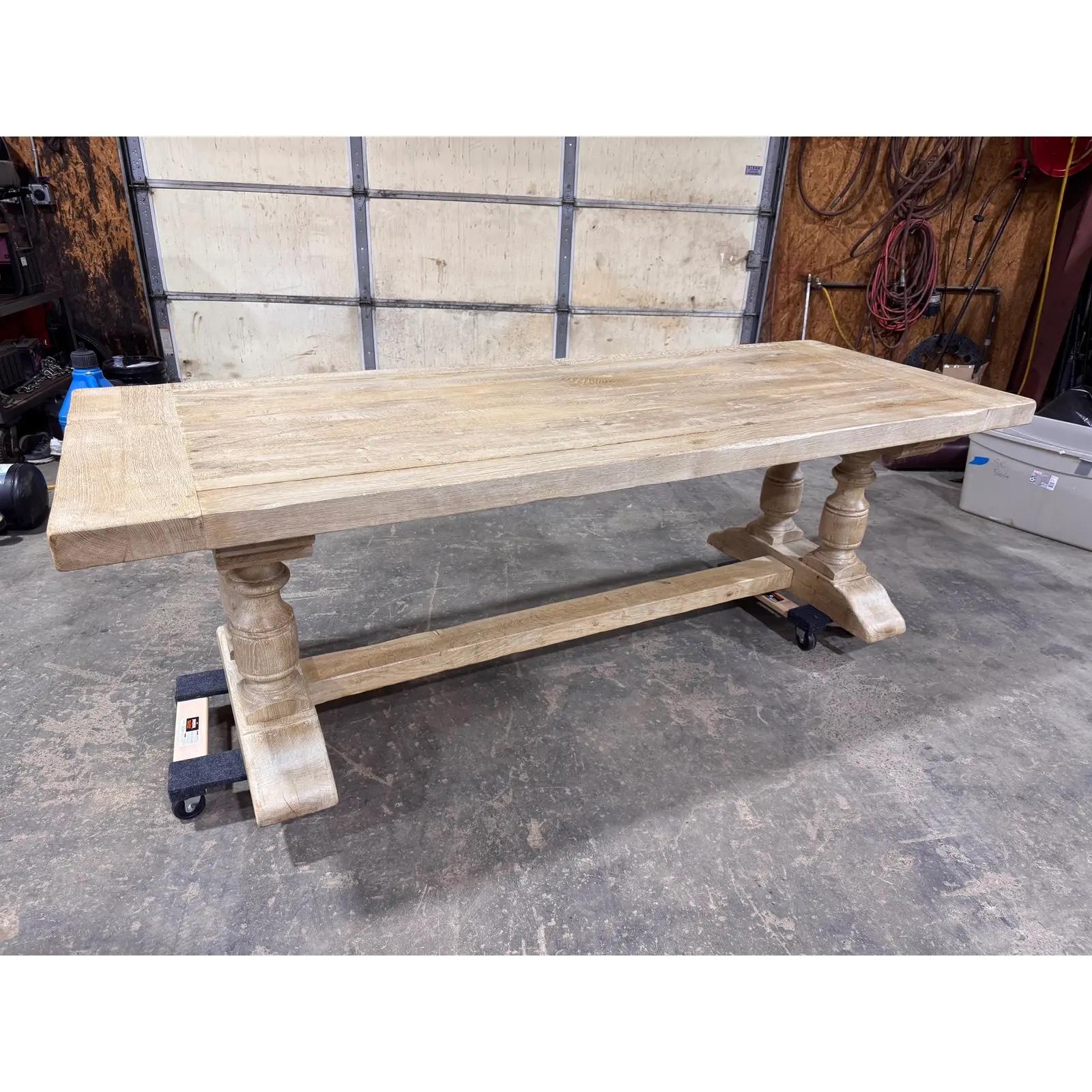 Cette table à tréteaux en pin massif présente une silhouette de ferme classique avec un piédestal tourné supportant une base robuste. Sa finition légèrement altérée ajoute de la chaleur et un caractère organique, mettant en valeur le grain naturel