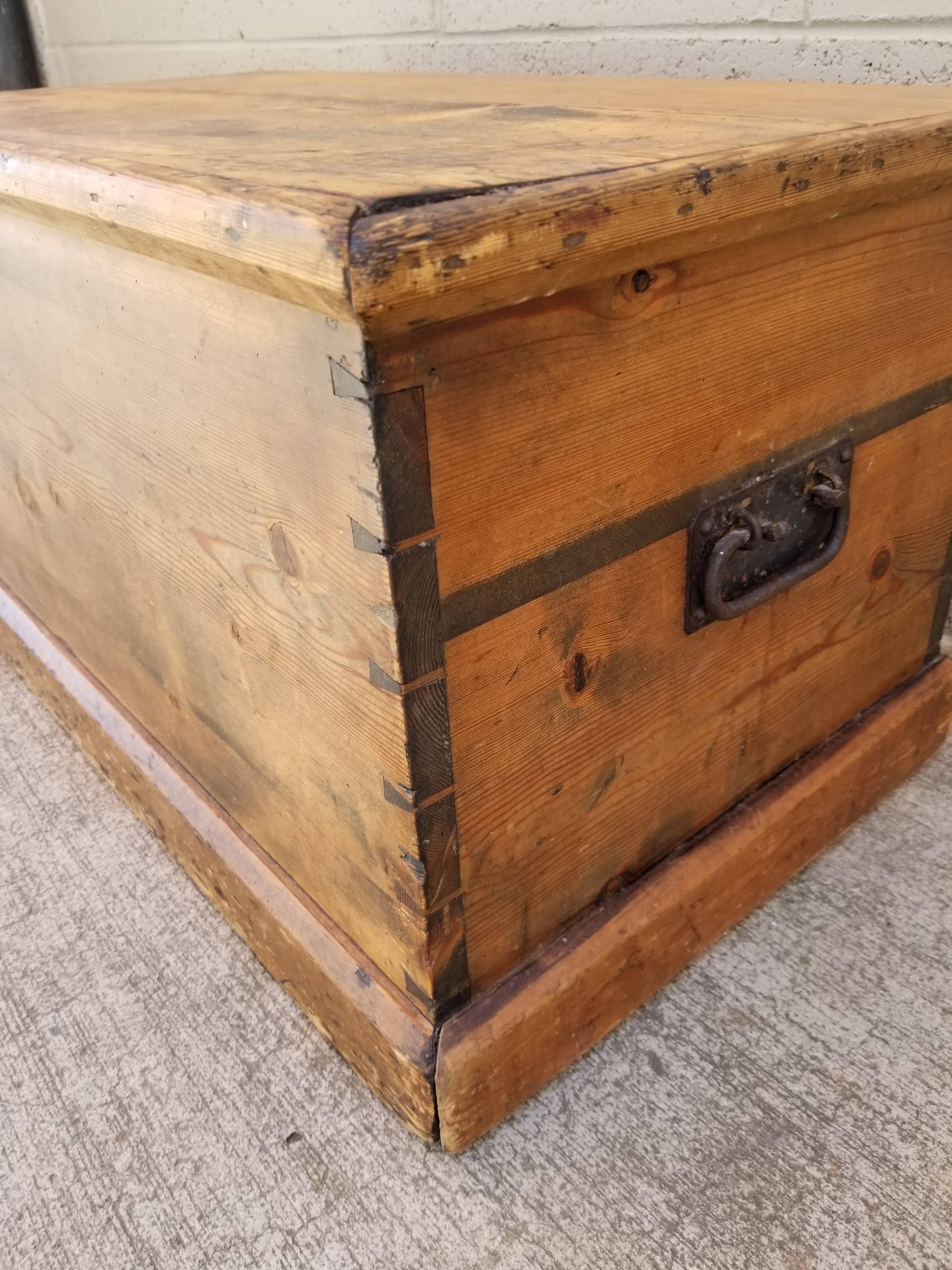 A late 19th century pine trunk. Exposed hand scribed dovetail. All original iron hardware intact, including lock. Would work well as a coffee or end table offering additional storage.