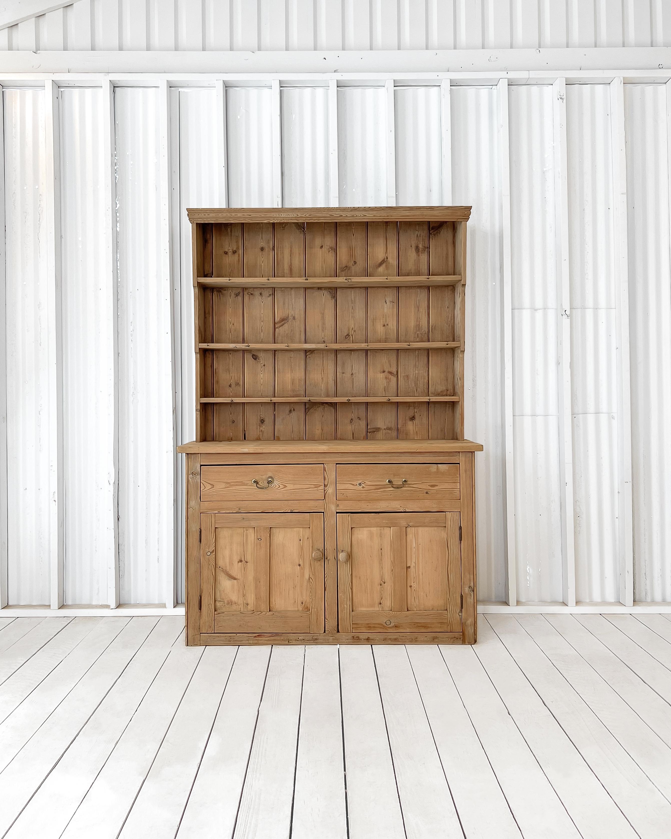 Found in Wales, circa 1850, this antique Welsh step-back cupboard is crafted from solid English pine with a wonderful distressed patina. Consisting of two separate pieces, the top of the dresser is fitted with a three-shelf plate rack that rests