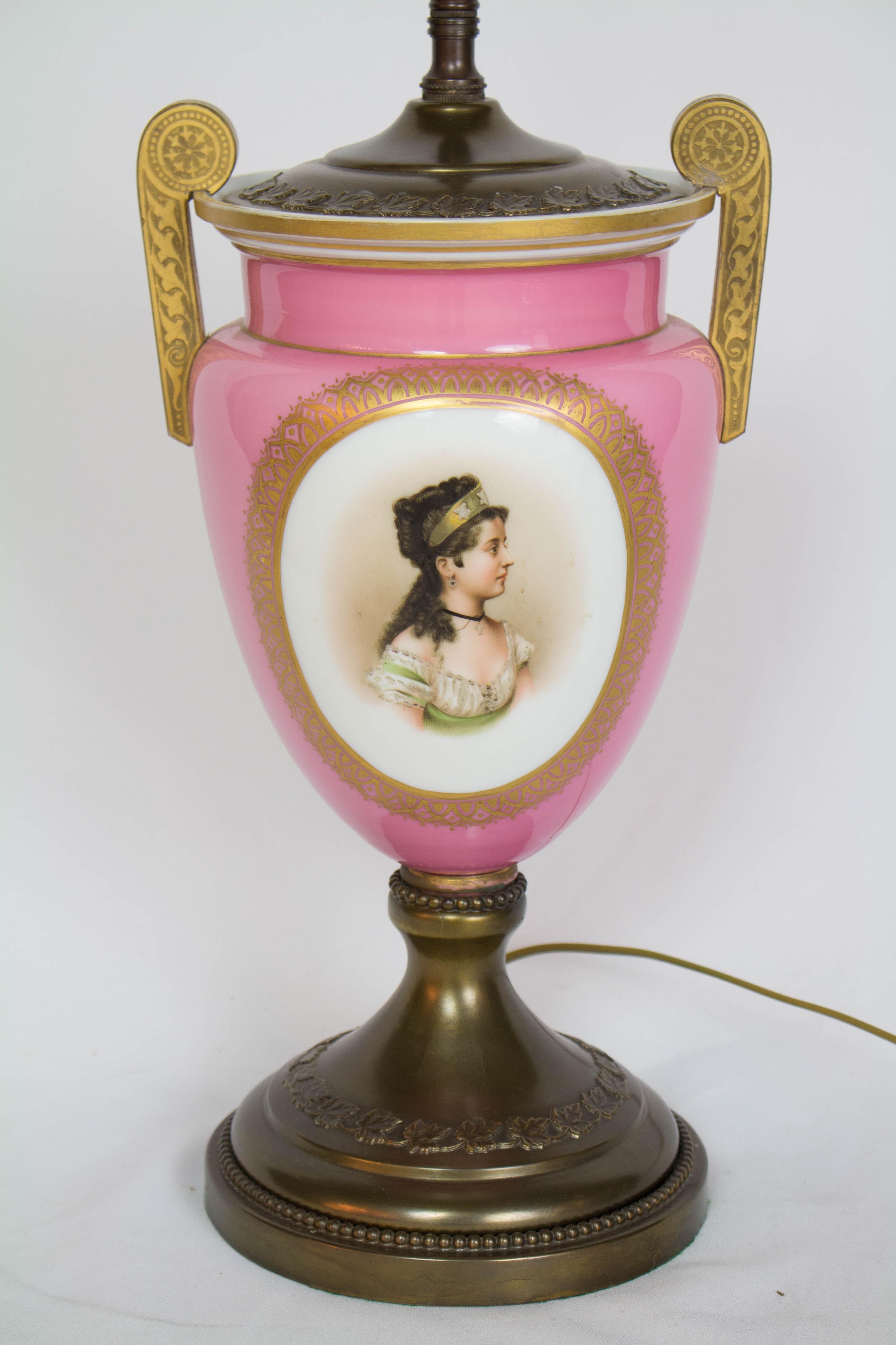 Pink portrait table lamp.  Portrait of a young woman on a cased glass and enamel urn with metal base.  The portrait was made with very fine detail with a detailed gold border.  Bohemian, 19th Century, C. 1880.  Made into a lamp in the early 20th