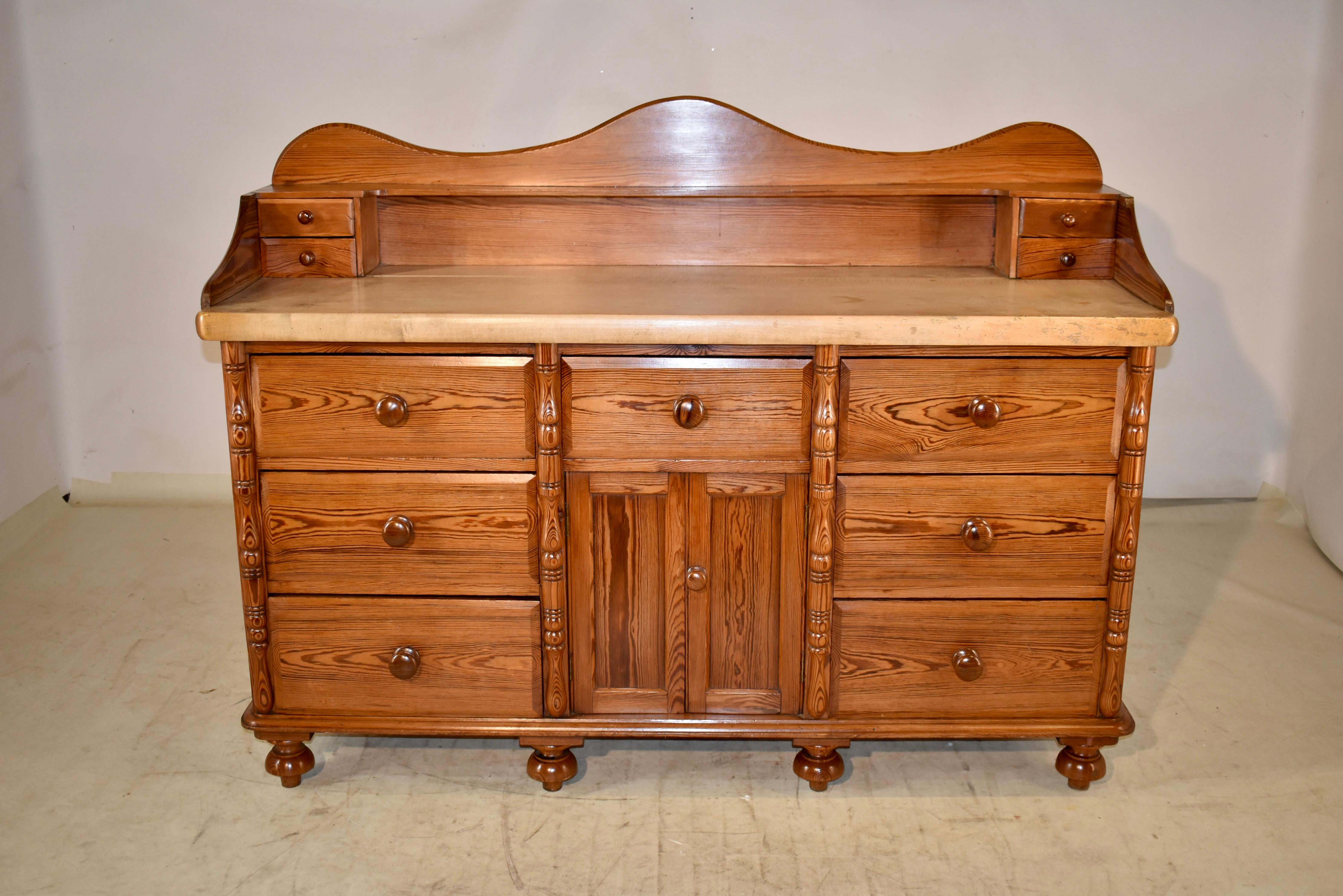 Early 19th century pitch pine sideboard with a gorgeous 2 inch thick sycamore top. The backsplash is scalloped and has a single shelf, which has set of drawers on either end of the piece. The serving surface is a 2 inch thick sycamore plank, which