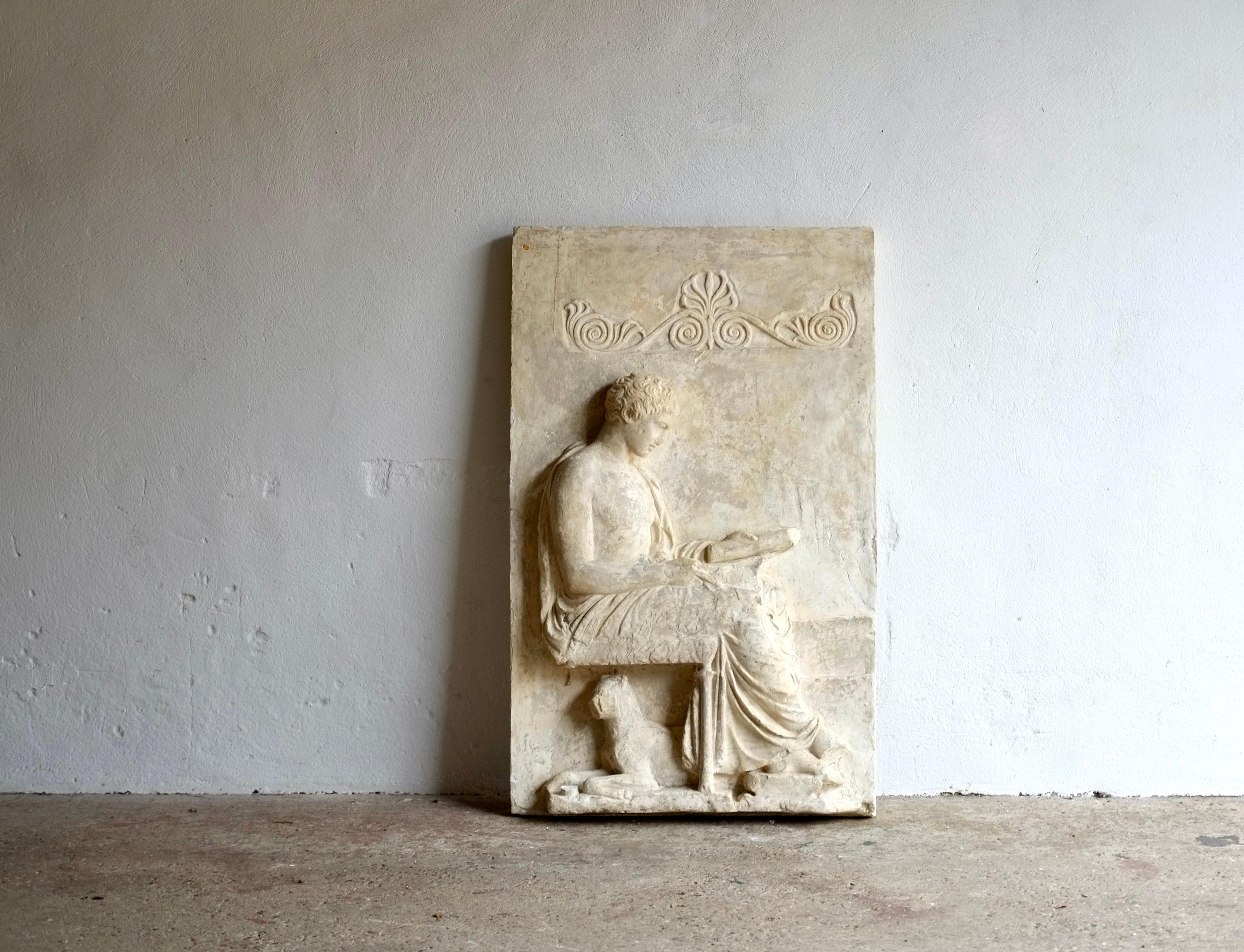 An impressive 19th-century plaster casting from the Grottaferrata marble grave stele. The Greek scholarly youth sits with his dog beneath his stool.

Provenance - From the collection of master plaster caster Peter Hone. 

Small loss next to the