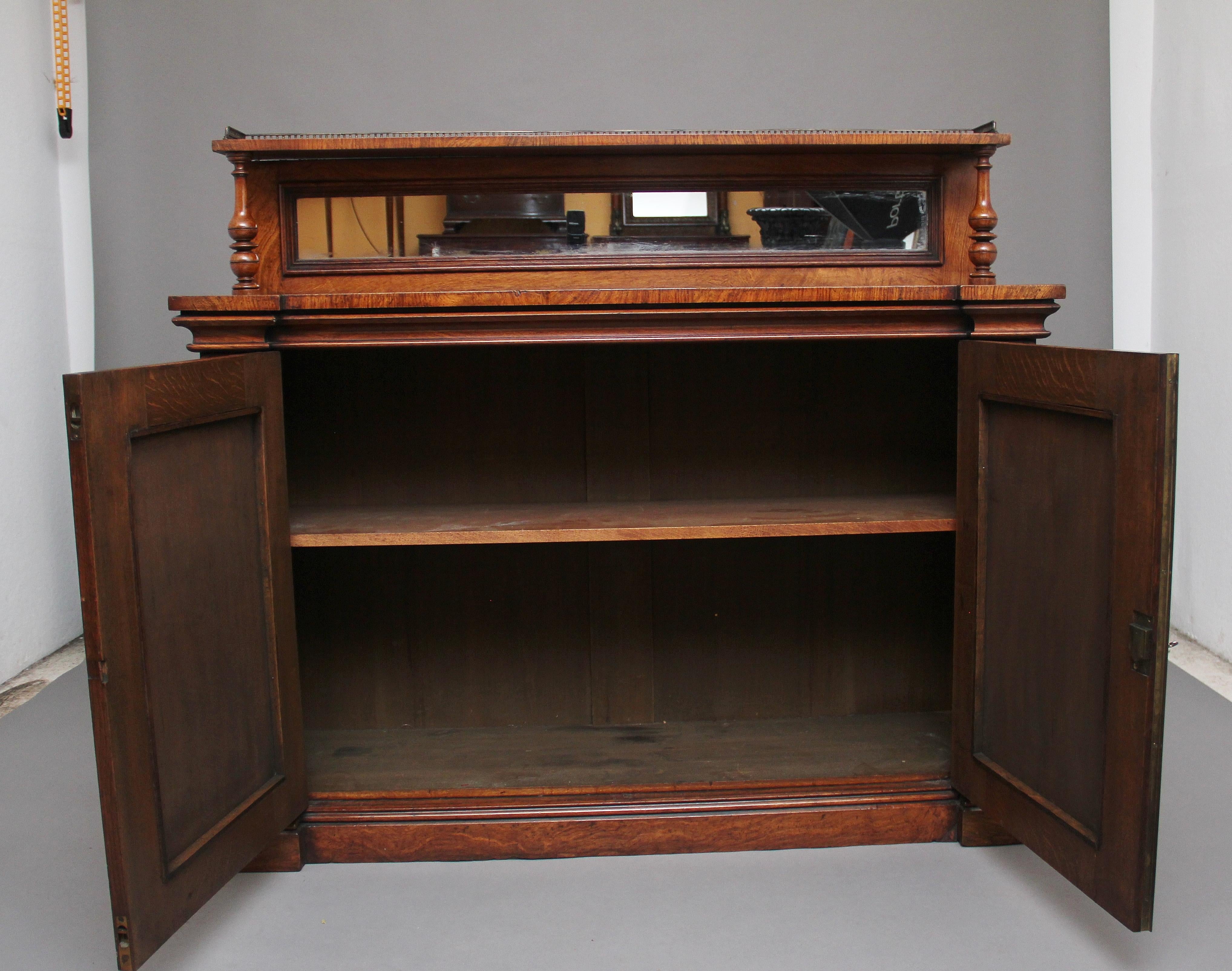 A lovely quality 19th century pollard oak cabinet or chiffonier, having a mirrored shelf superstructure with three quarter brass gallery, supported on turned columns, wonderfully figured top above two doors with pleated material panels opening to