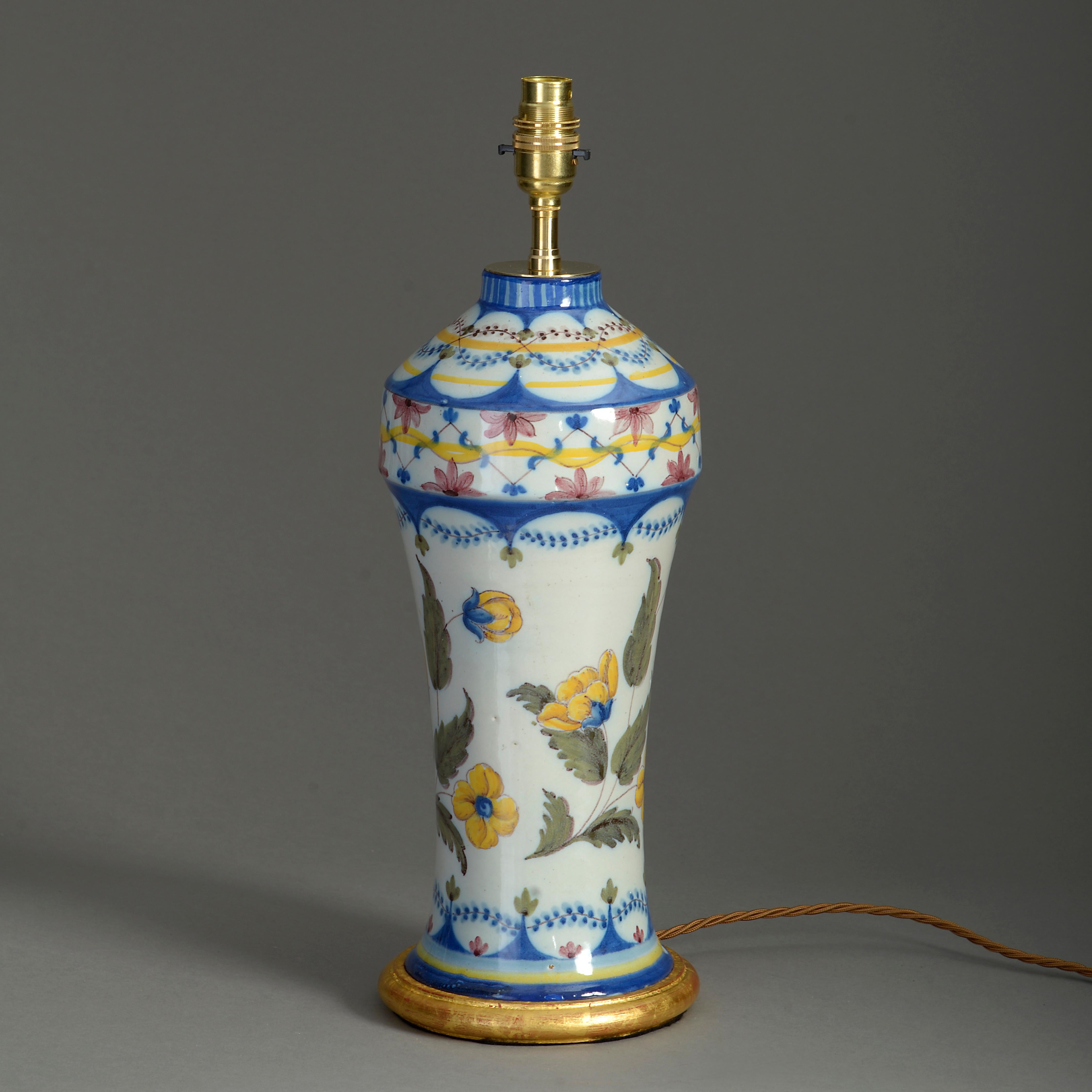 A charming late nineteenth century faience vase, decorated with polychrome glazes depicting flowers and foliage on a white ground. Now mounted as a lamp base and set upon a hand-turned water gilded base.

Dimensions refer to height of