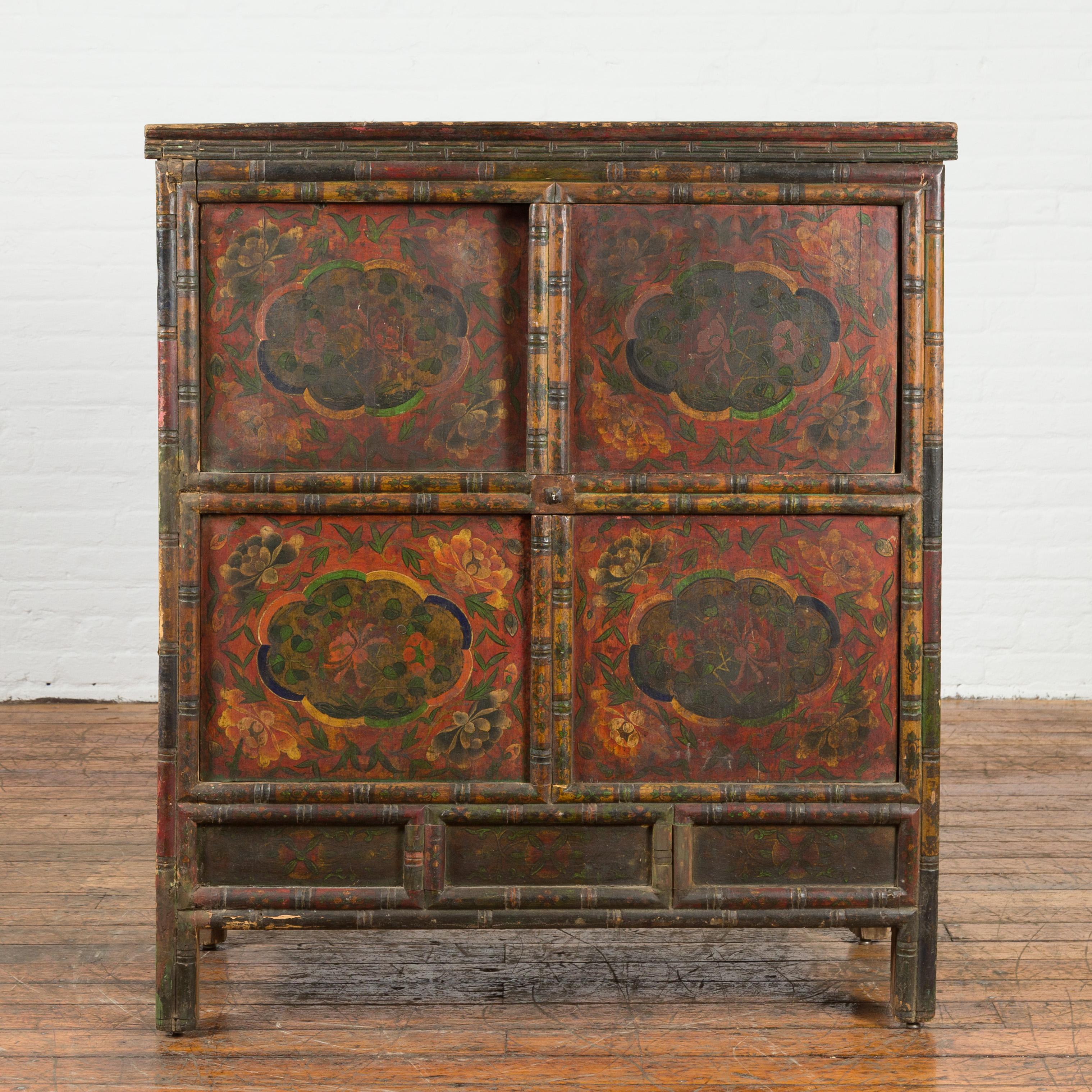 A Tibetan antique cabinet from the 19th century, with painted cartouches and two pairs of double doors. Created in Tibet during the 19th century, this cabinet features a painted façade made of two pairs of double doors adorned with colorful