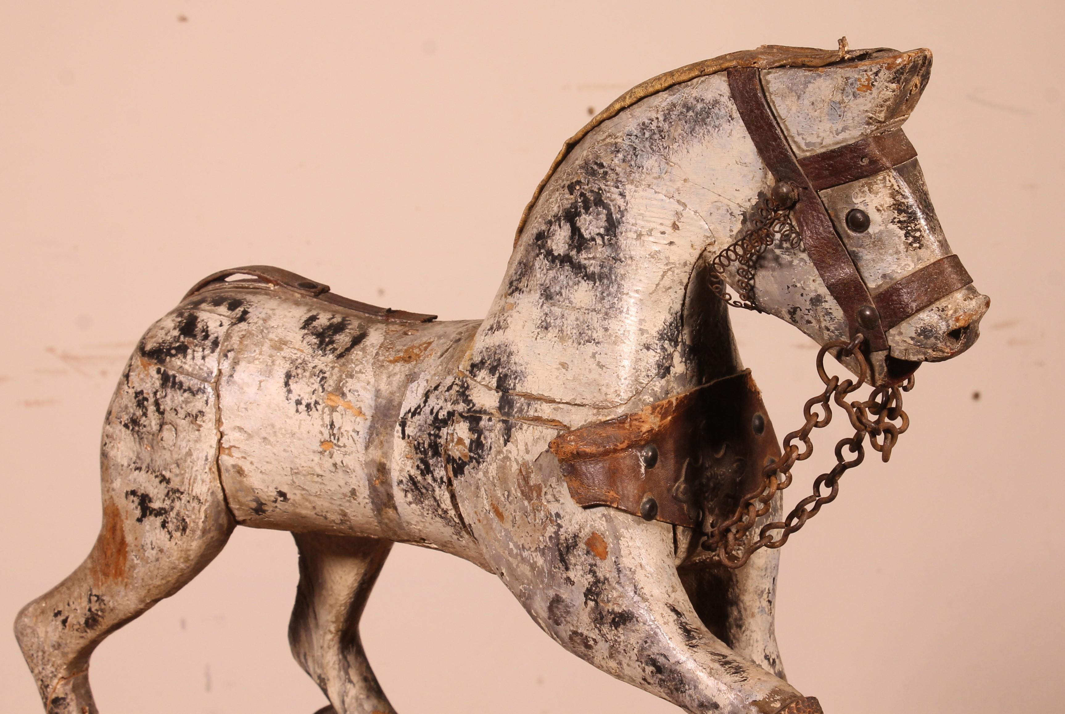 Elegant little carved wooden horse from the 19th century in polychrome wood

Very beautiful polychromy which has a lot of charm
Old child's toy with the front wheels which moves
In good condition given its age and use
Very nice patina.
 
