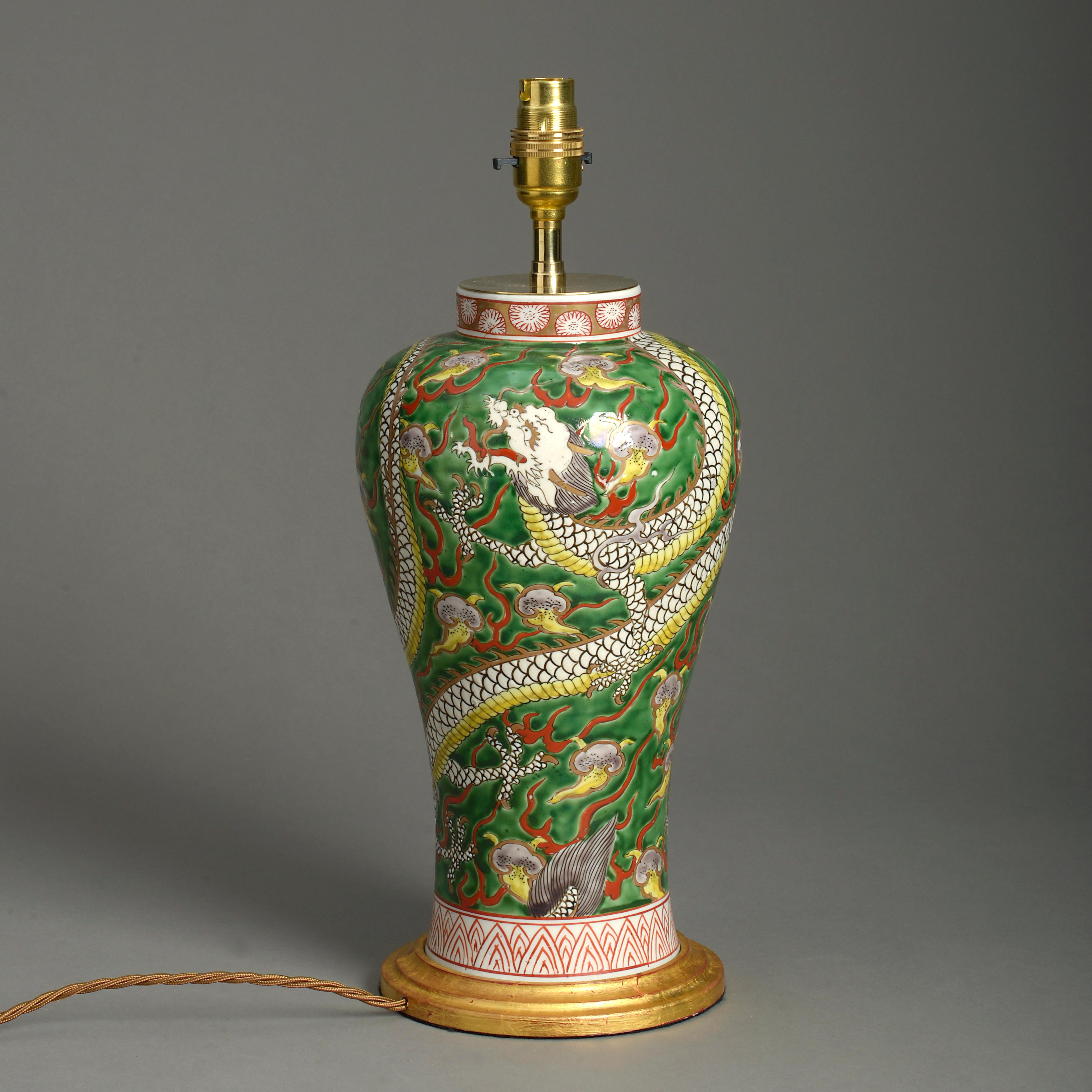 A late 19th century baluster form vase, the body decorated with a polychrome dragon upon a green glazed ground. Now mounted as a lamp and set upon a turned giltwood base.

Dimensions refer to height of vase and base only.

Wired and tested for