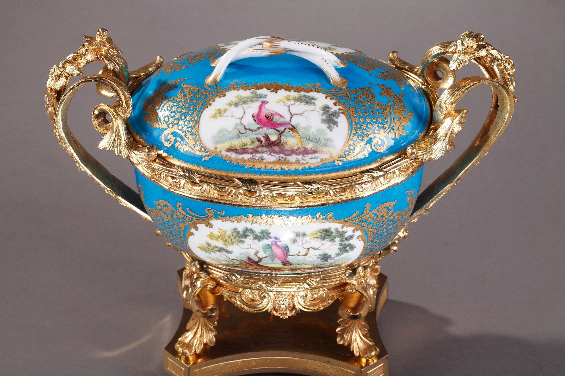 Small bronze-mounted porcelain covered pot in Sevres style. The turquoise, or bleu celeste, background highlights the exquisite polychromatic plaques featuring birds on branches, surrounded by foliated gilt borders. Bronze ormolu stands, richly
